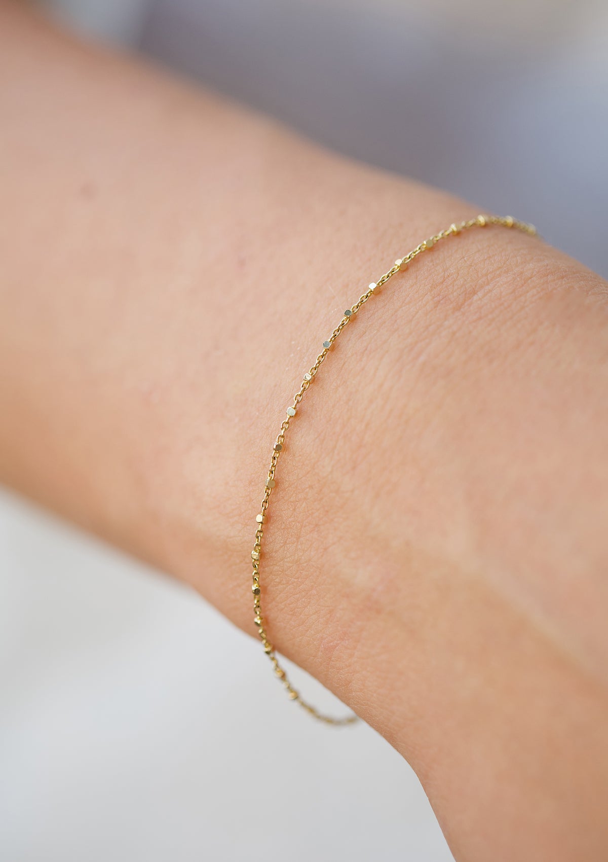 Delicate gold cube bracelet worn on wrist – solid 14K gold minimalist jewelry