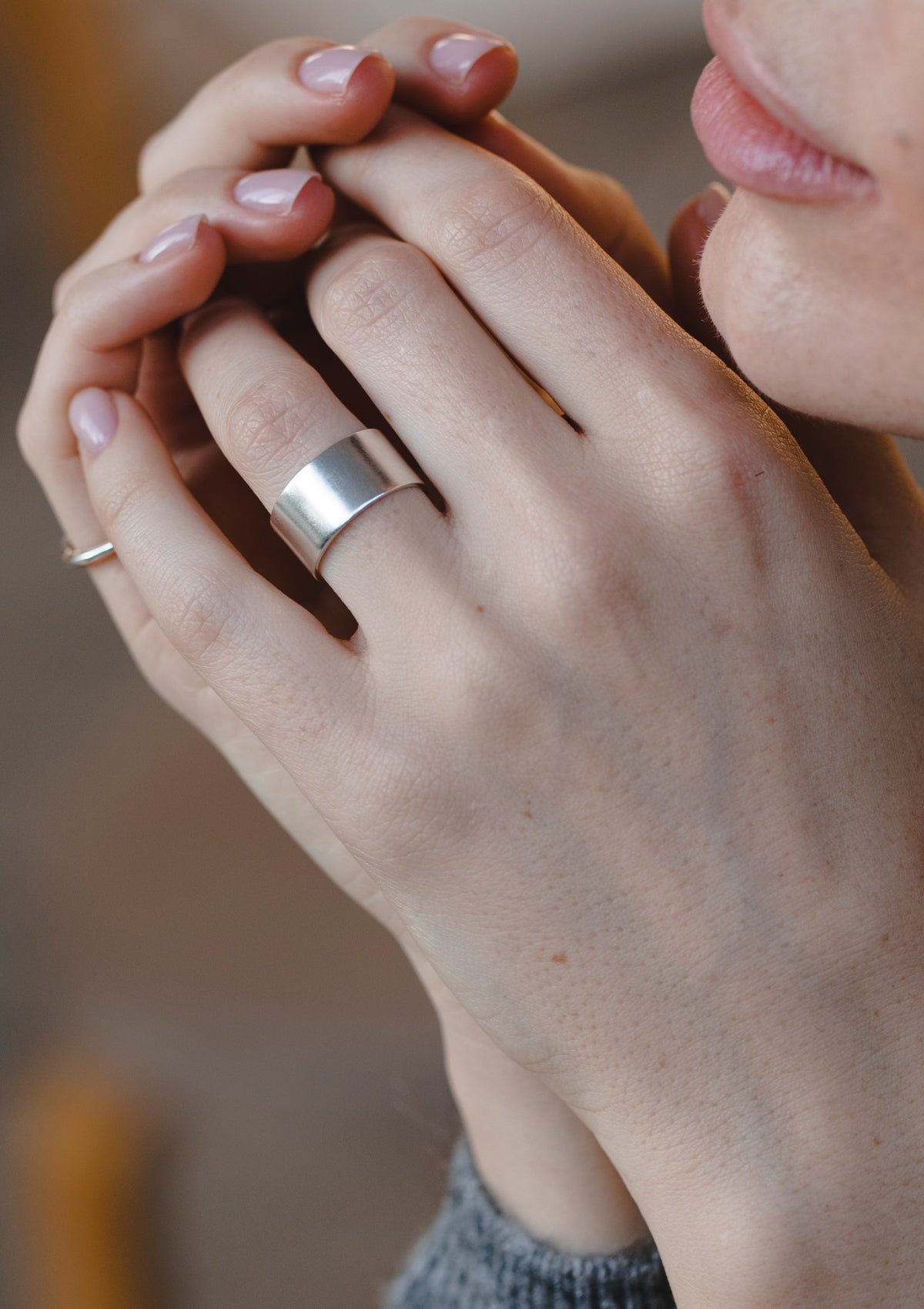 Thick silver thumb ring with smooth surface, worn for a bold modern look on natural hand