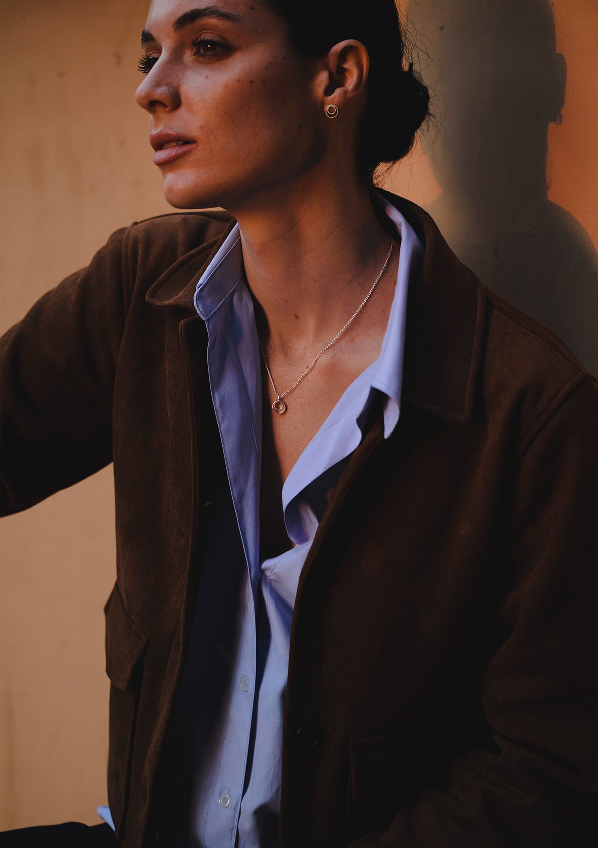 Small silver pendant necklace highlighting neckline, clean lines and simple geometry