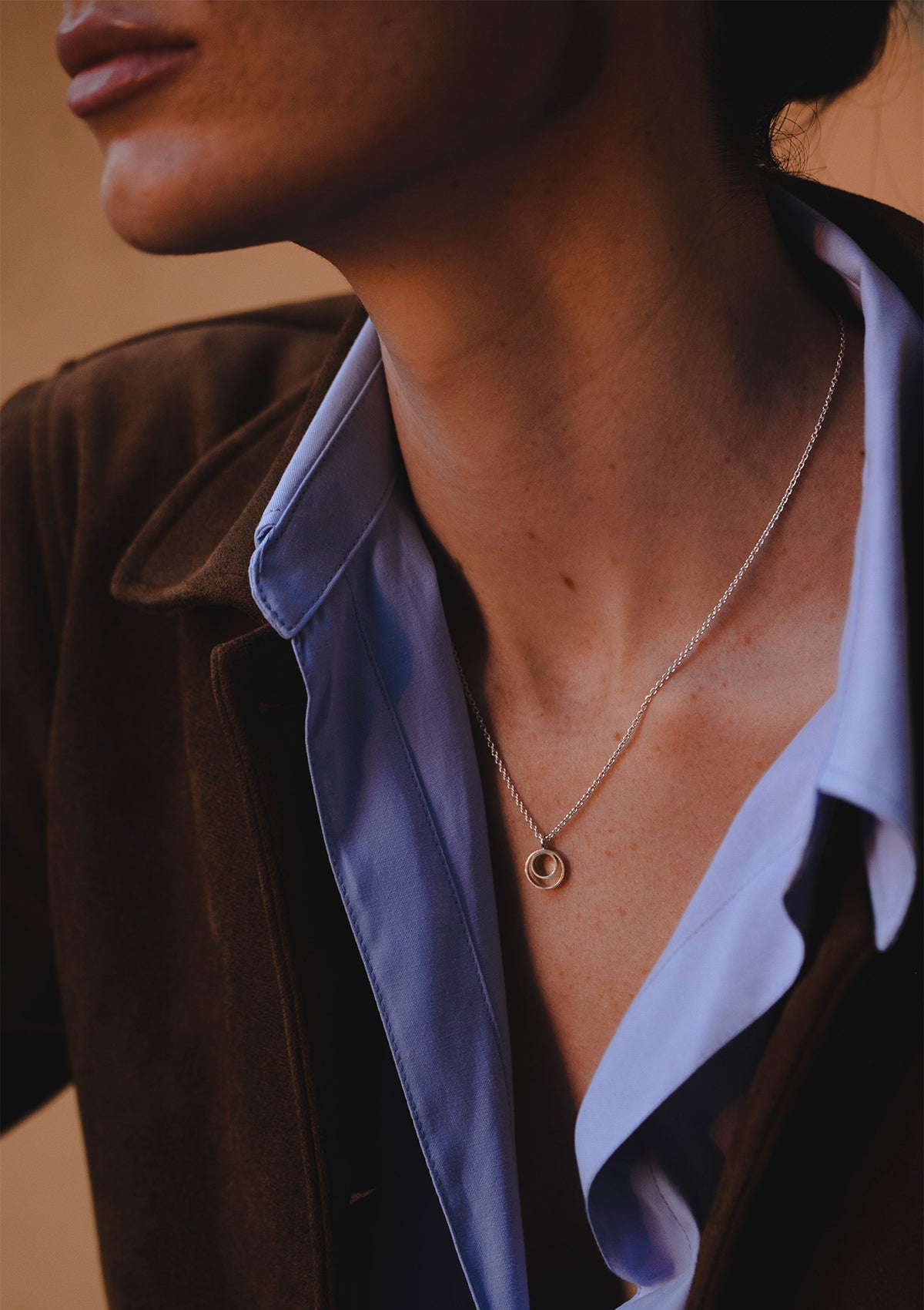 Modern geometric silver pendant necklace, styled in natural light for cozy, sophisticated feel
