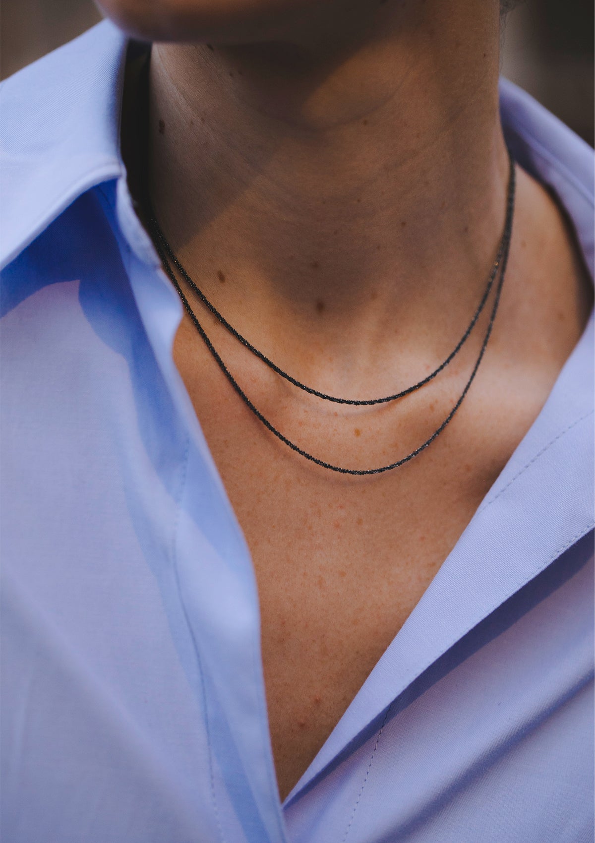 Model wearing oxidized sterling silver choker with subtle shine, styled with open collar