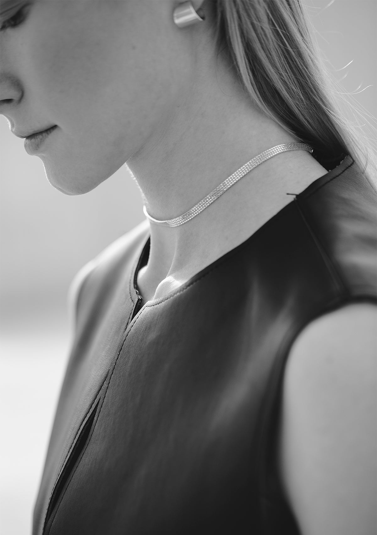 Rear close-up of silver choker and clasp detail on model's neck, polished finish, clean minimal look