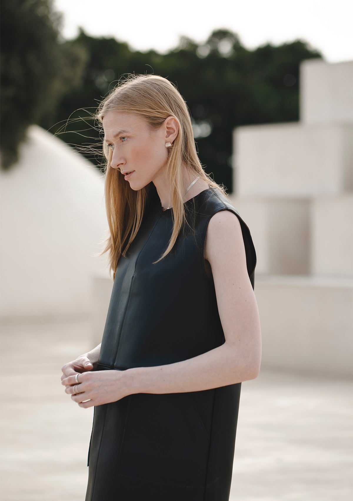 Model in black sleeveless dress wearing silver choker, architectural backdrop for minimalist elegance