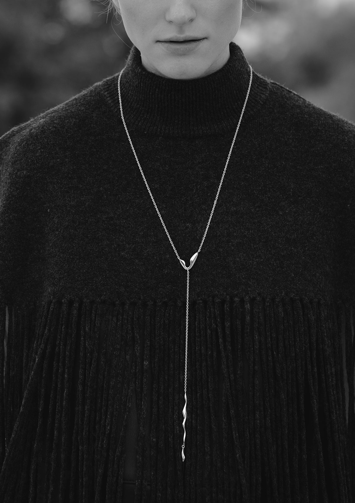 Monochrome view of long silver necklace with sculptural dangles, artisan jewelry for special occasions