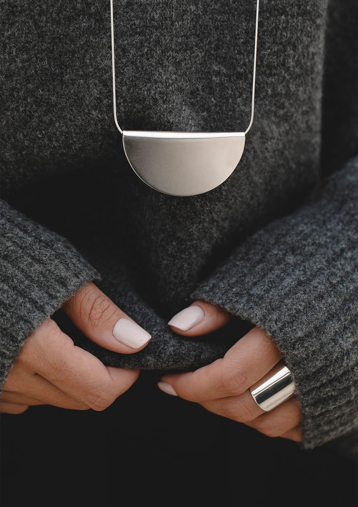 Bold handcrafted silver ring close-up with subtle matte sheen, styled for cozy everyday look with textured clothing