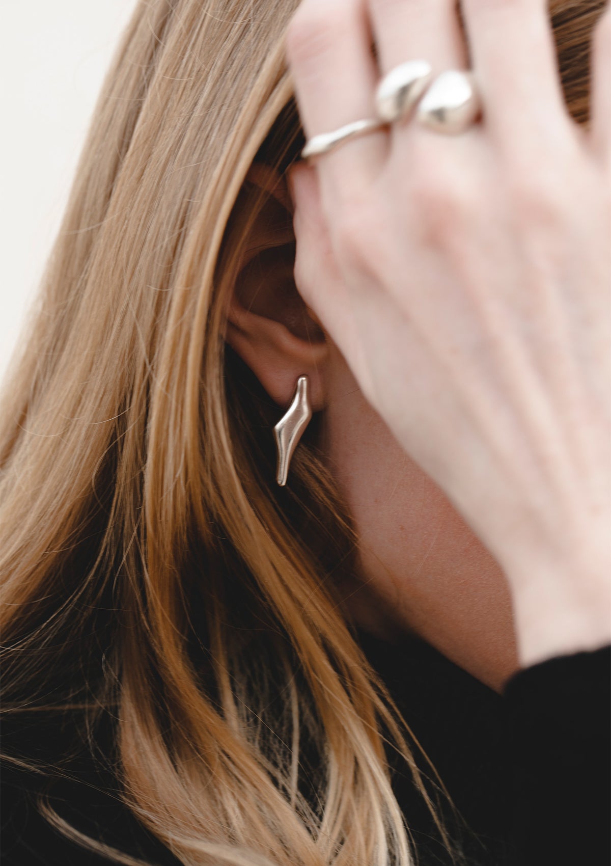 Tiny silver earrings worn close to the ear, delicate handcrafted design with subtle organic shape