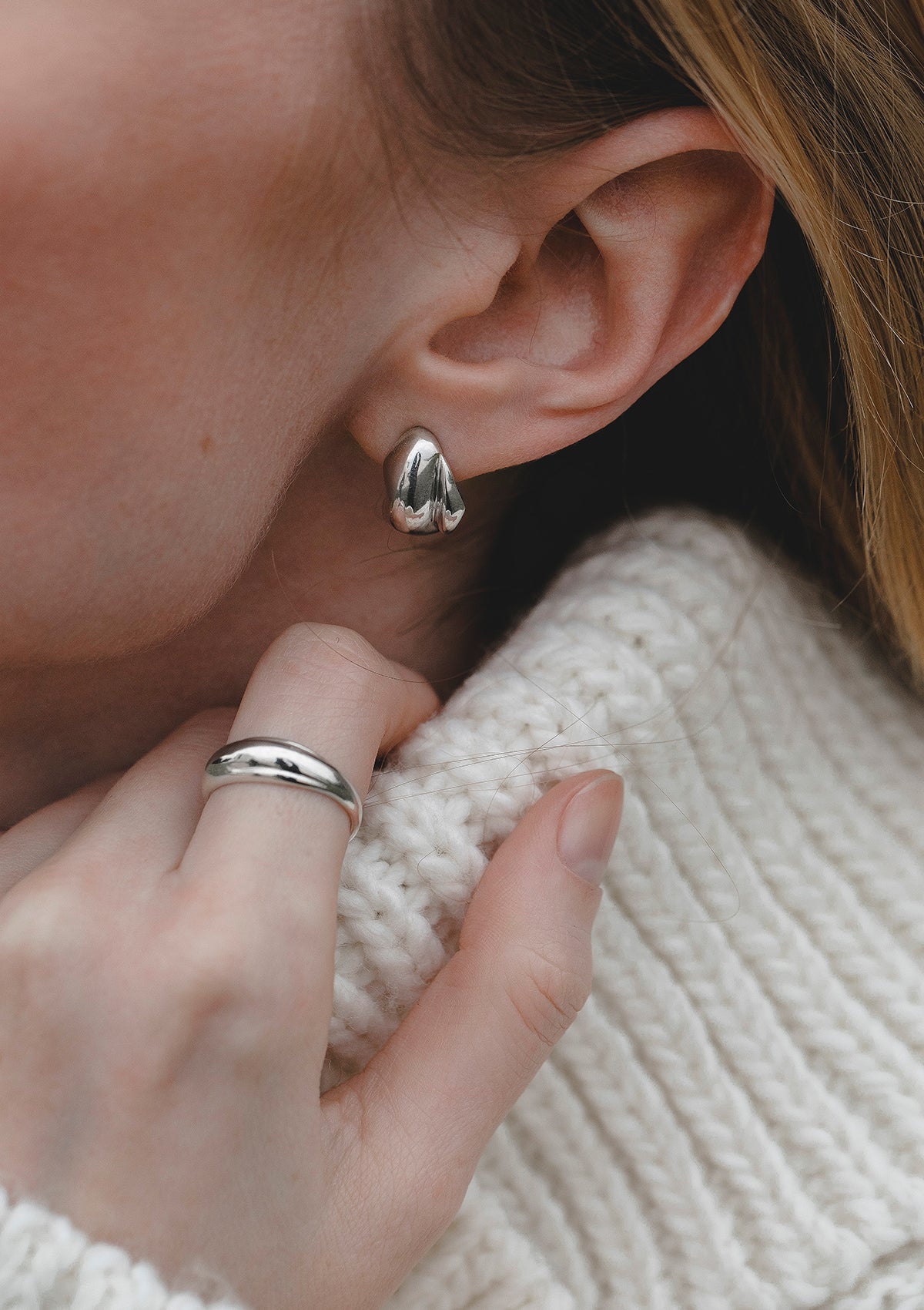Elegant sterling silver dome ring worn on finger, refined minimal jewelry styled with neckline