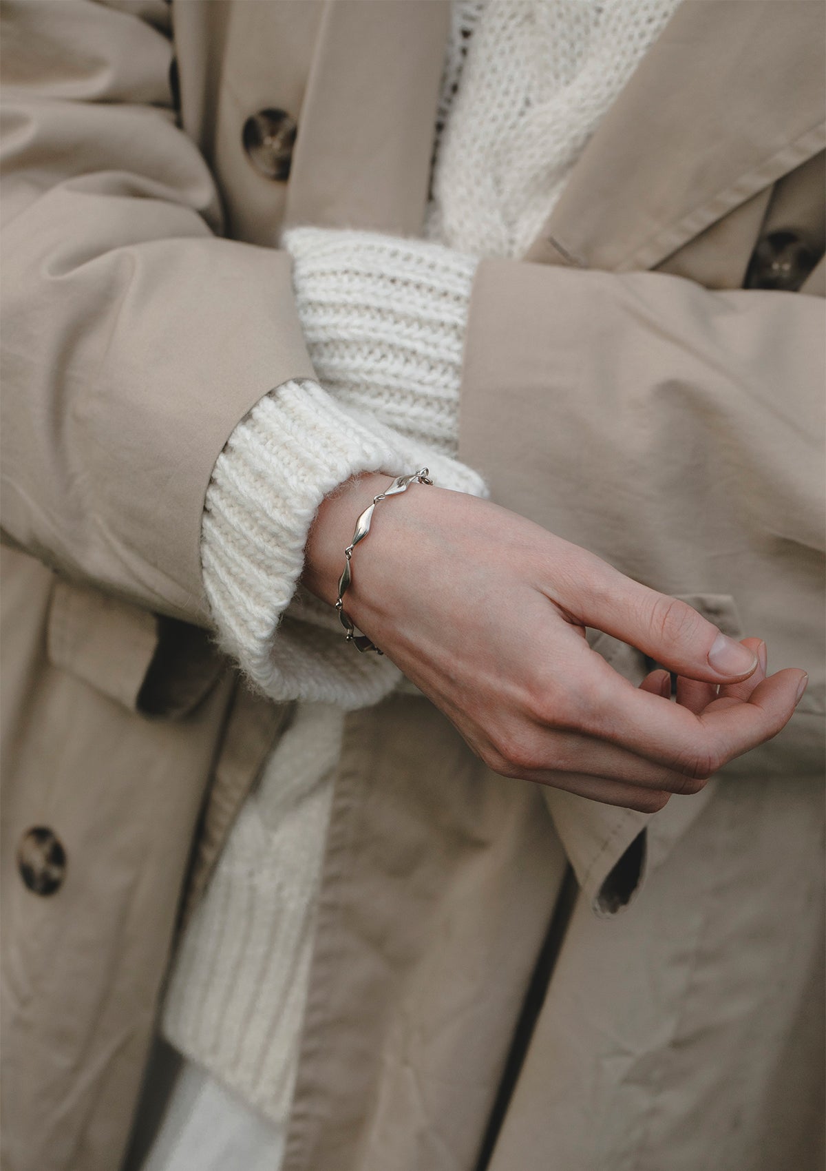 Statement wave bracelet in solid silver, sleek handcrafted piece styled with neutral outerwear