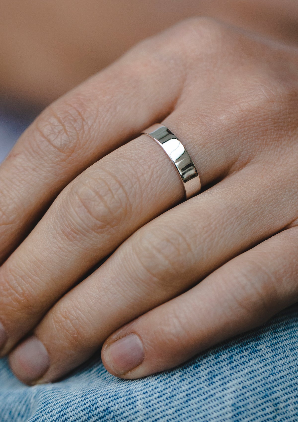 Sterling silver ring with smooth polished shiny surface, worn as a classic modern band on hand