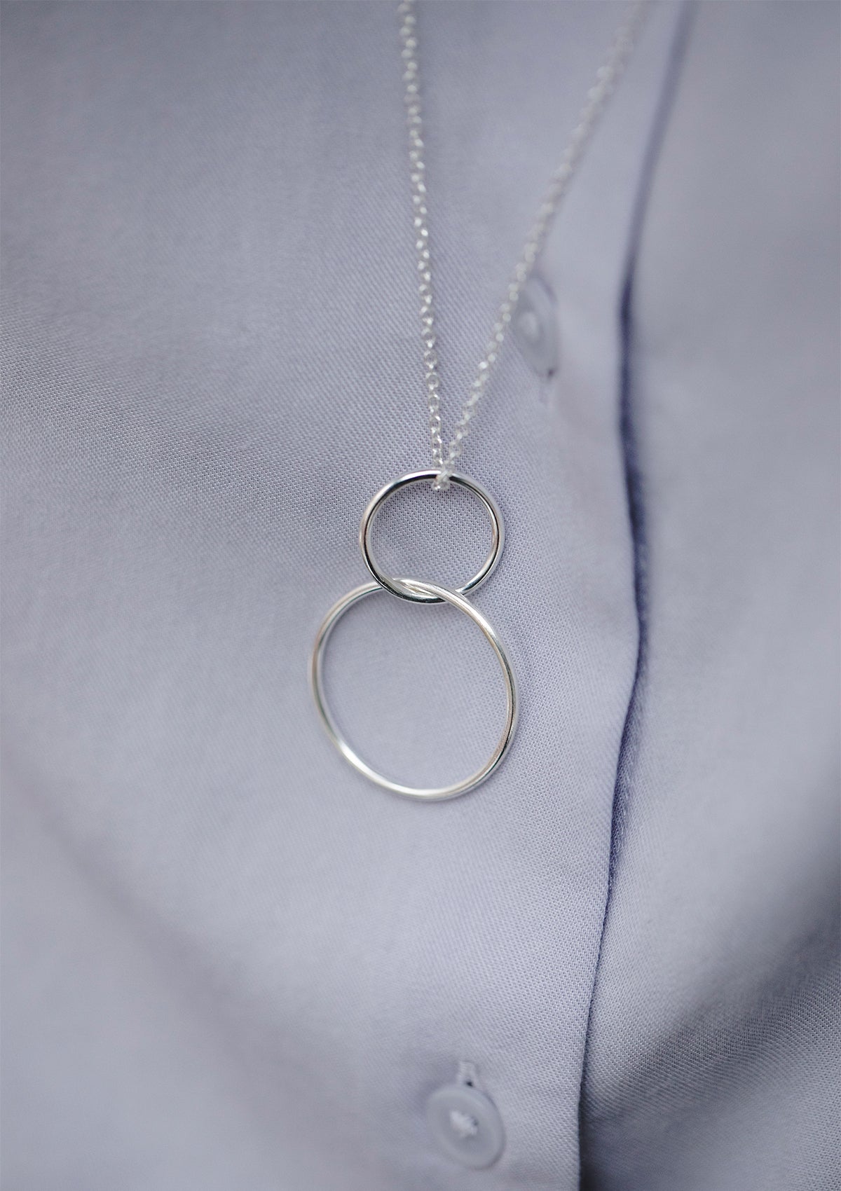Double hoop pendant on long silver chain, minimalist necklace styled against blue shirt