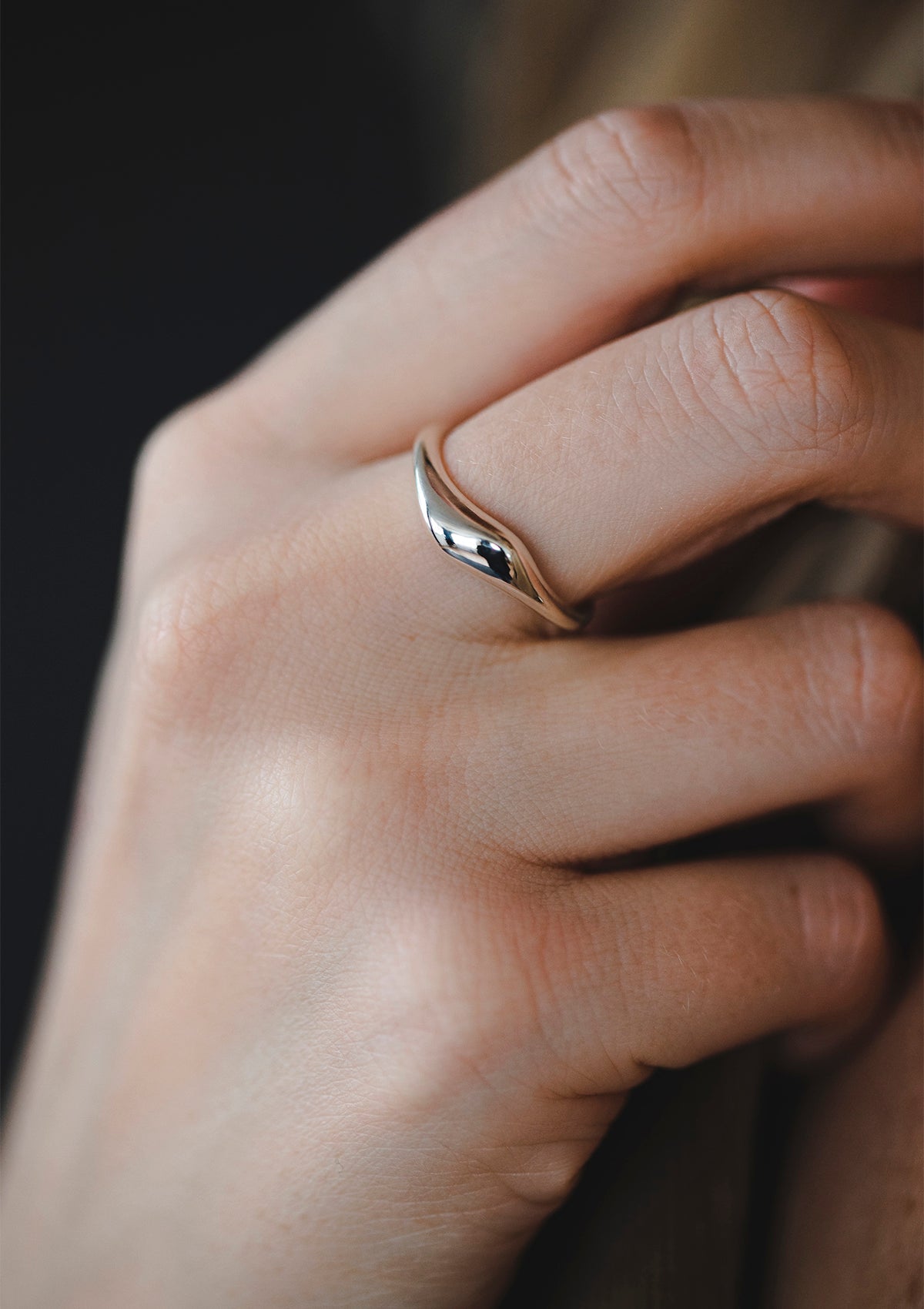 Minimalist sterling silver ring with sweeping contour on hand