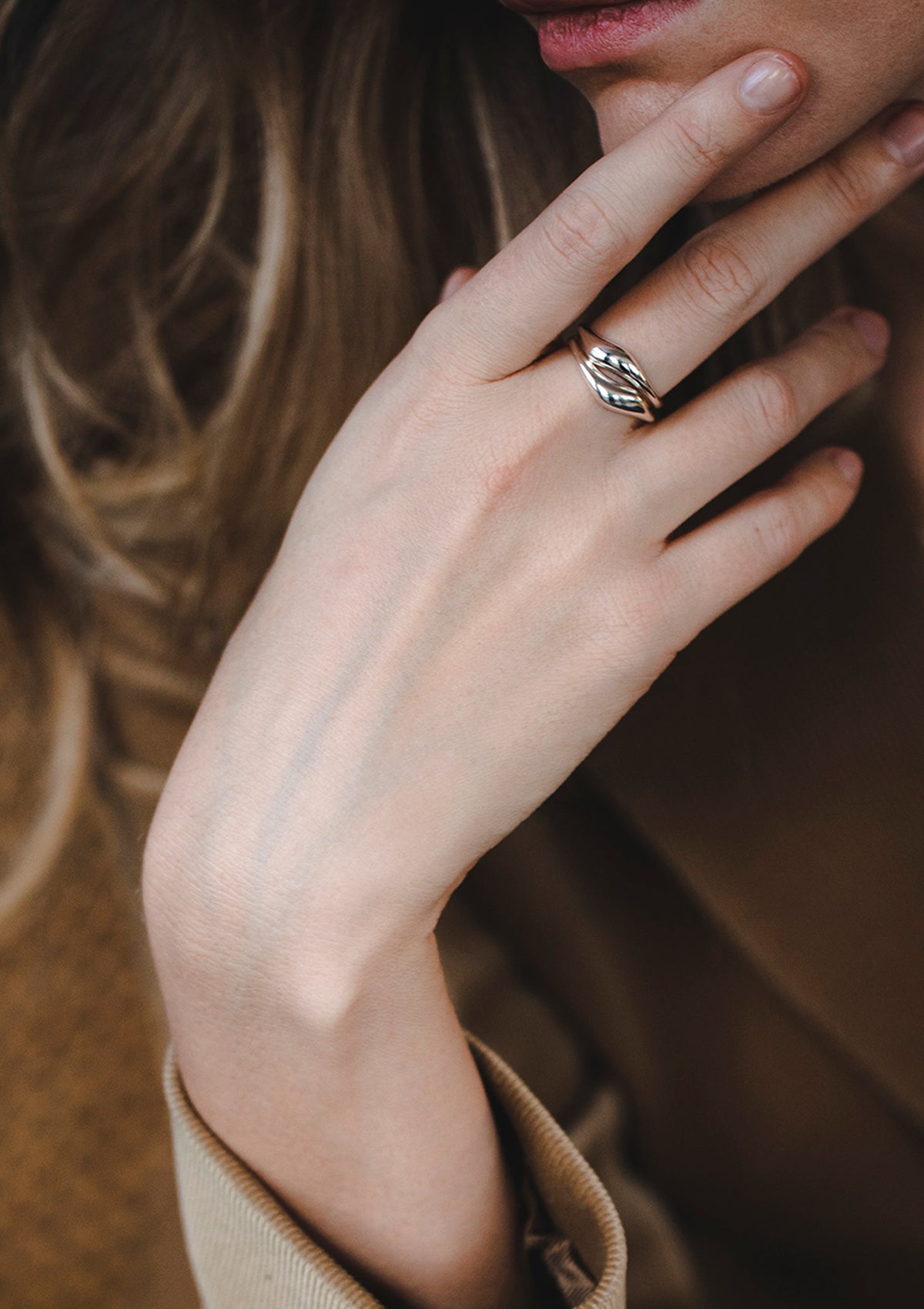 Curved sterling silver wave rings worn on finger, elegant jewelry styling