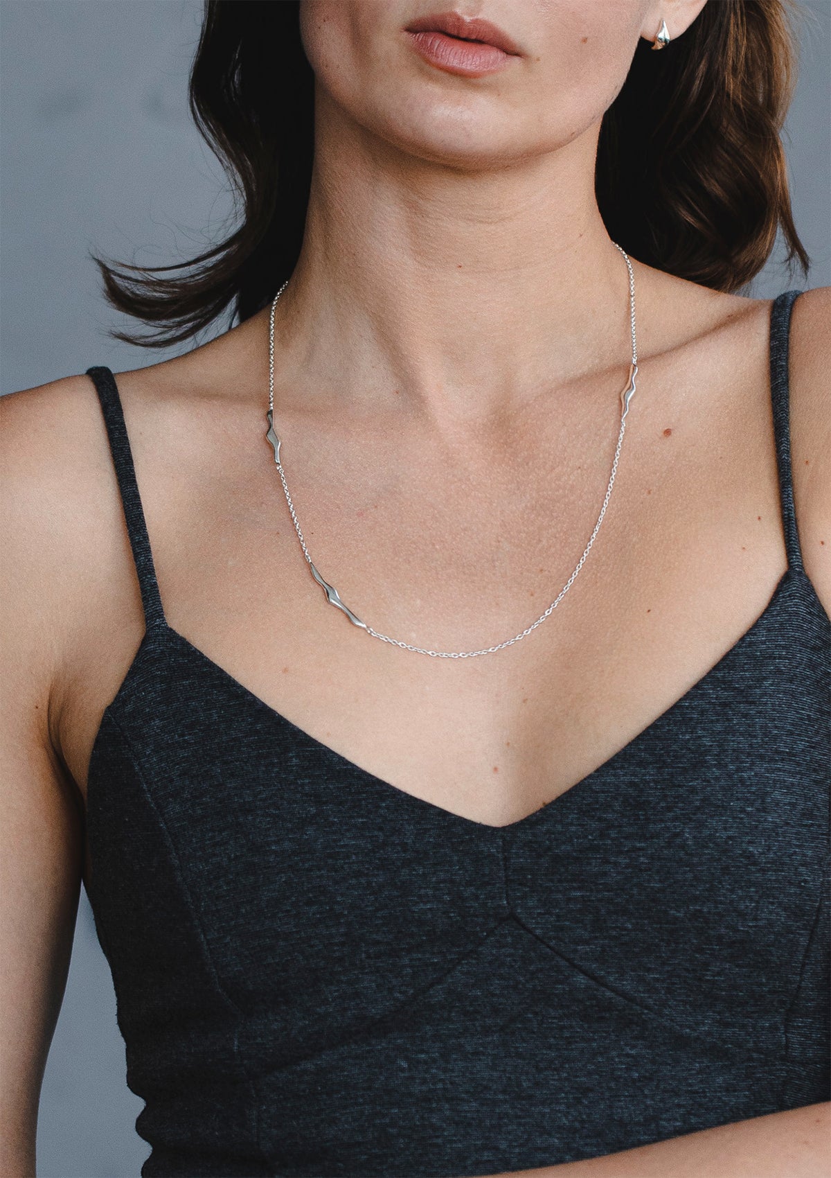Sleek sterling silver necklace with curved elements, elegant artisanal jewelry styled with black top