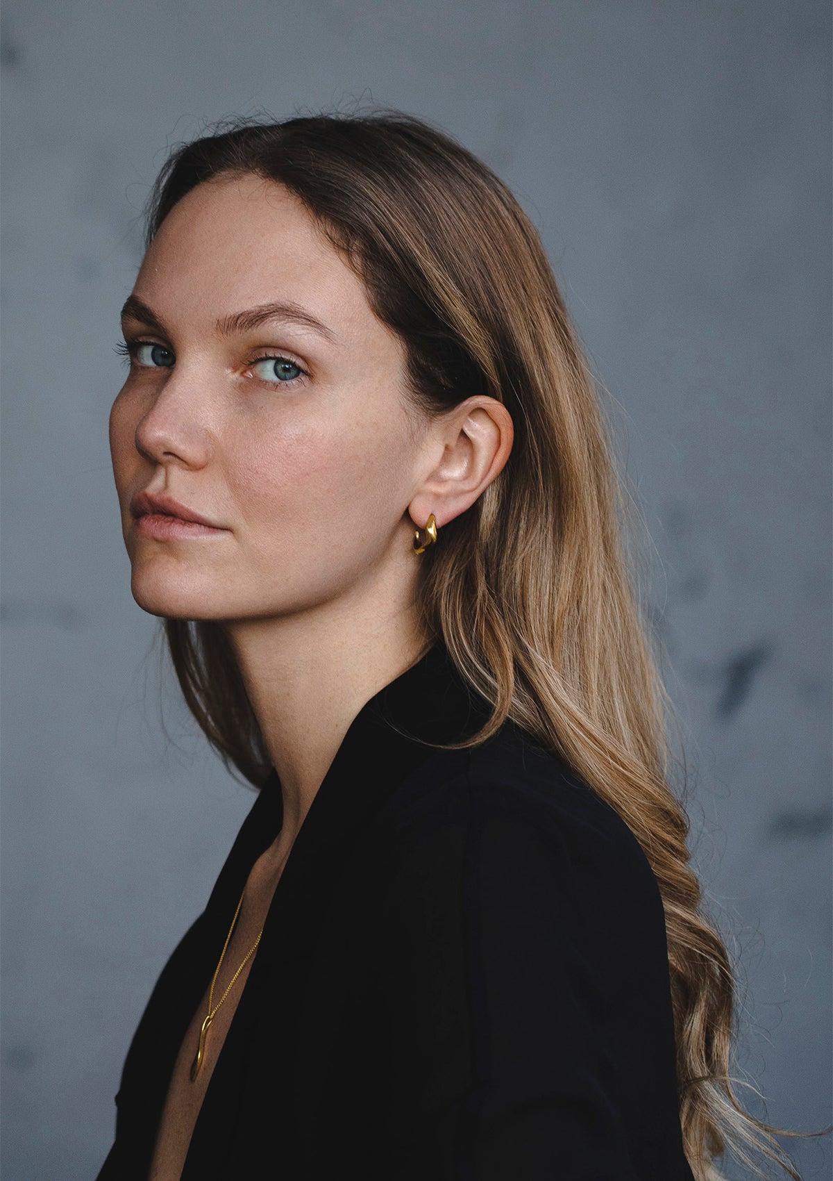 Contemporary 14K gold hoops with gentle curve, refined modern design worn close to ear