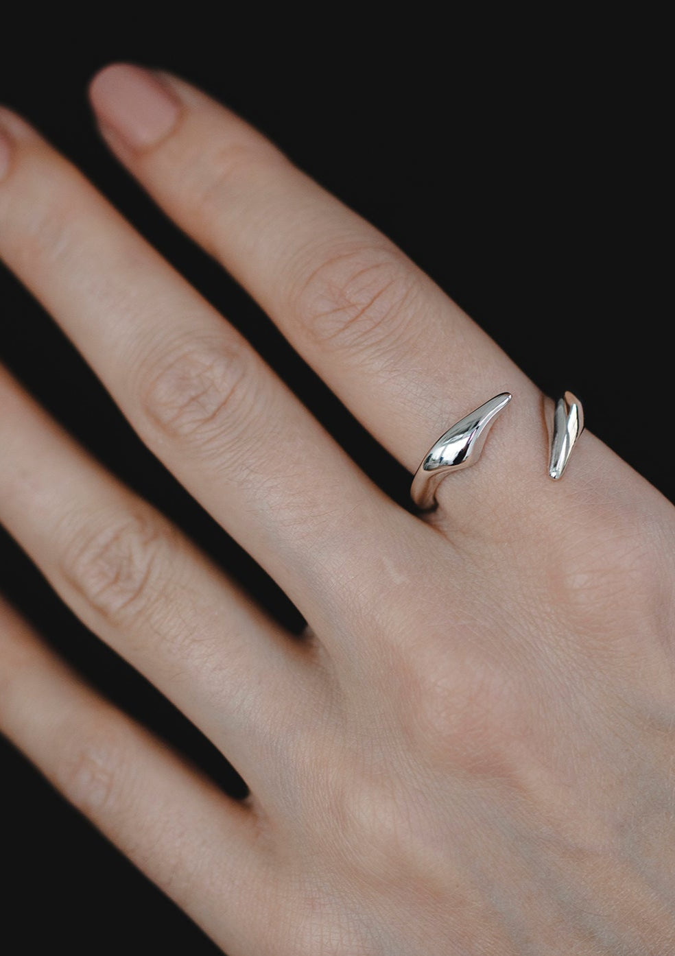 Adjustable sculptural silver ring with asymmetrical open ends, styled on hand