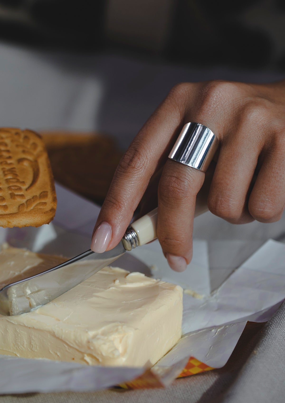 Statement silver ring styled during a meal, bold wide band reflecting light, adds modern contrast to lifestyle setting