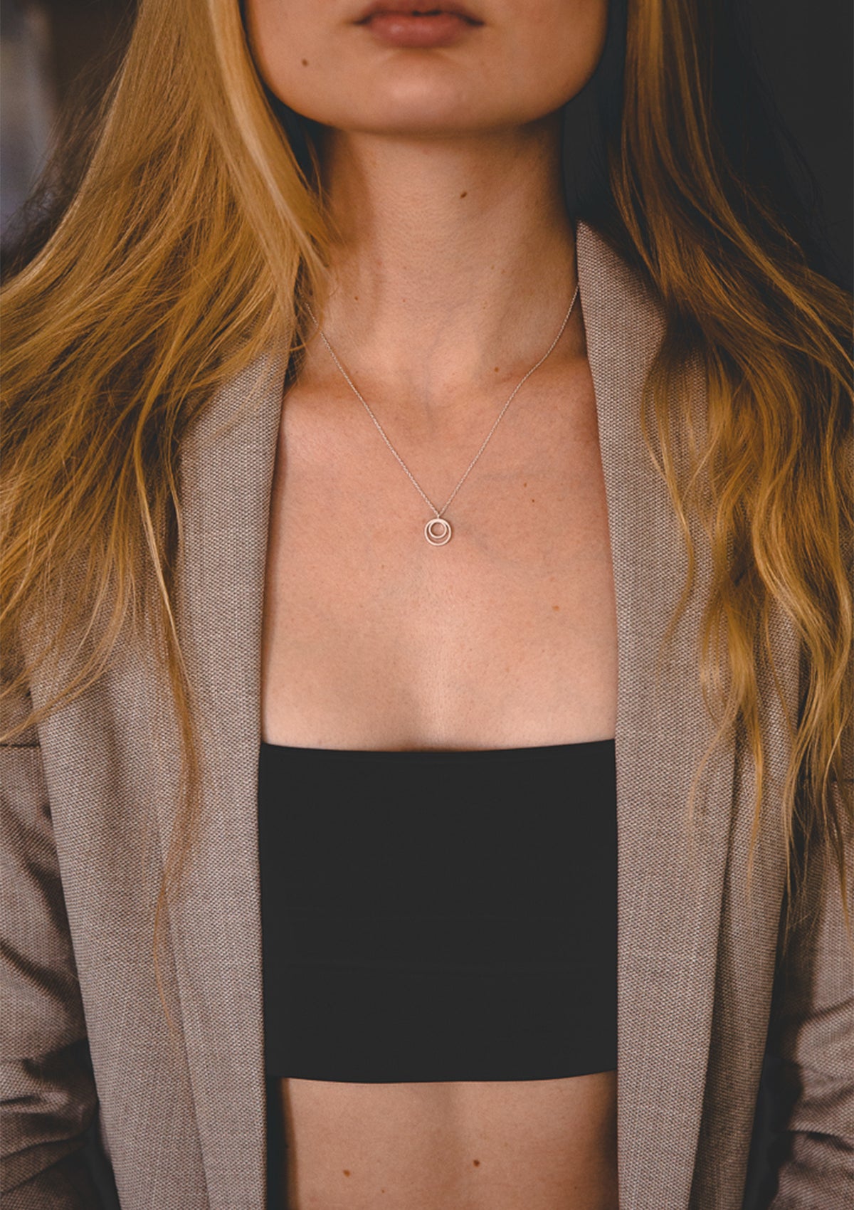 Sterling silver circle-in-circle necklace styled with tailored neutral blazer, timeless minimalist look