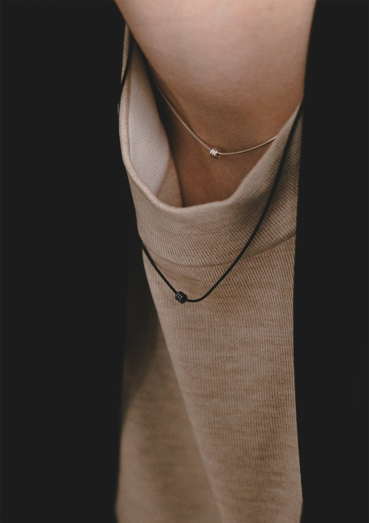 Minimalist sterling silver necklace with three small balls, styled over beige knit and black jacket