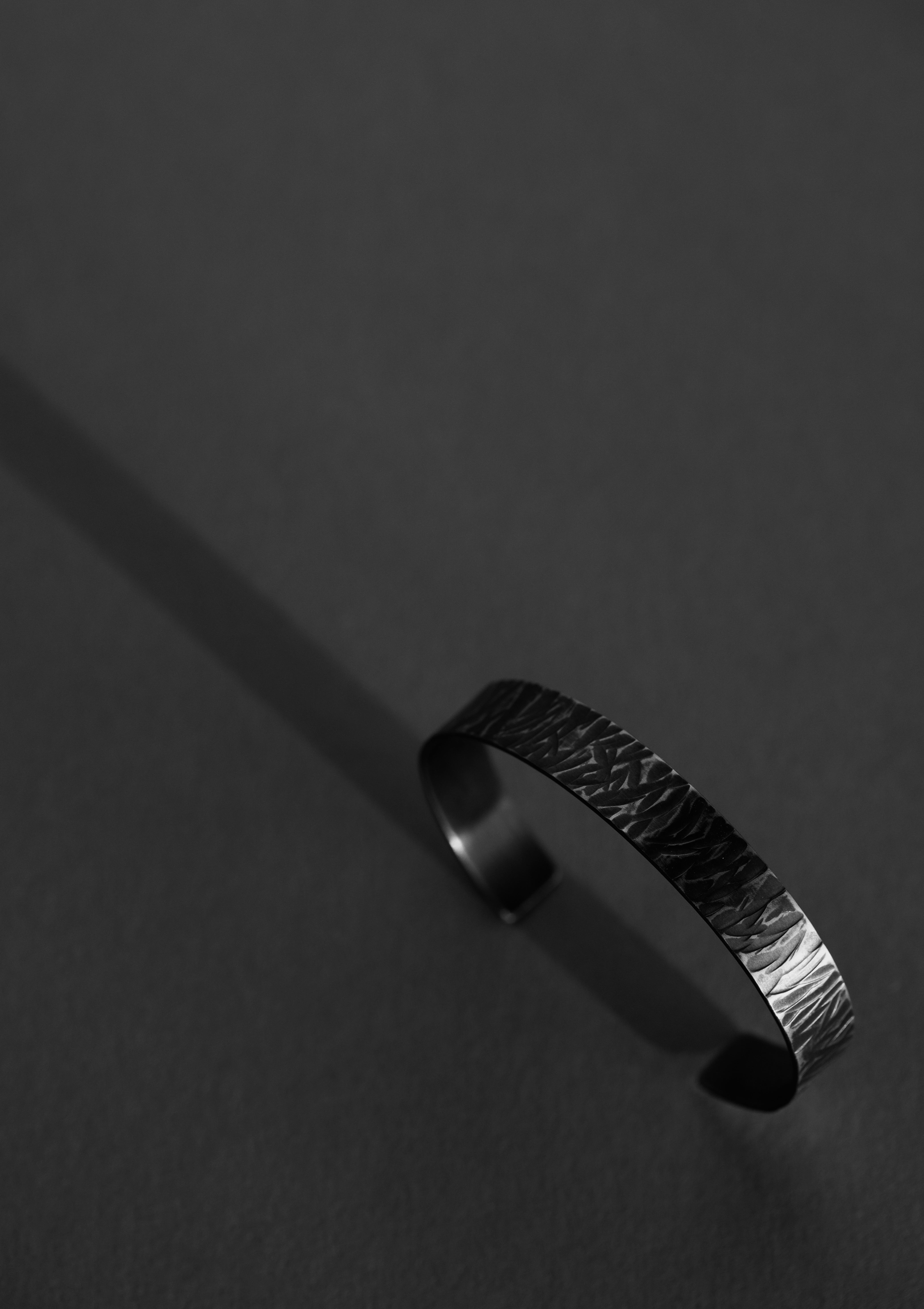 Oxidized silver bangle viewed from top, geometric form emphasized against dark background