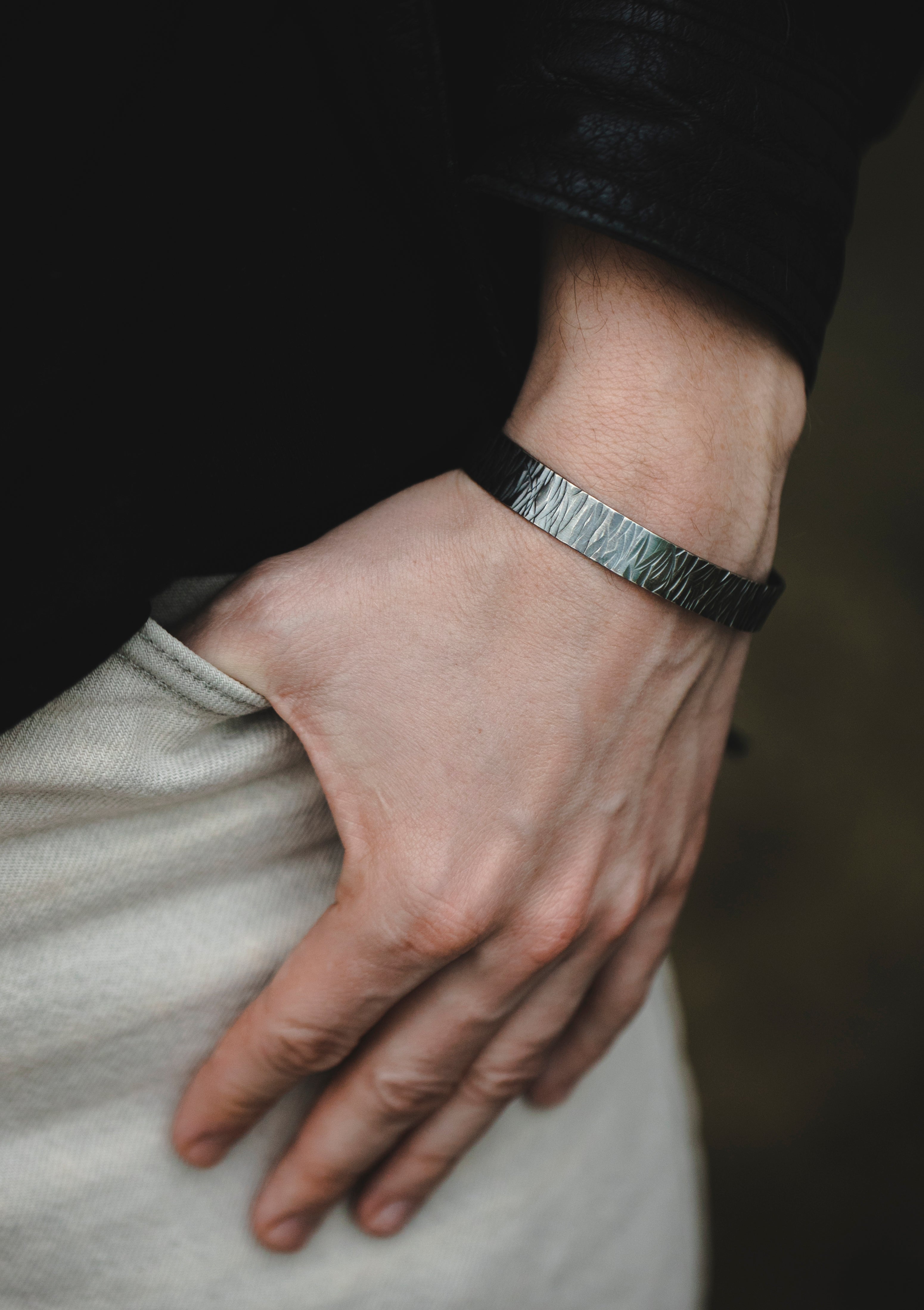 Men’s silver cuff bracelet styled in natural light, worn with relaxed clothing, highlighting matte patina