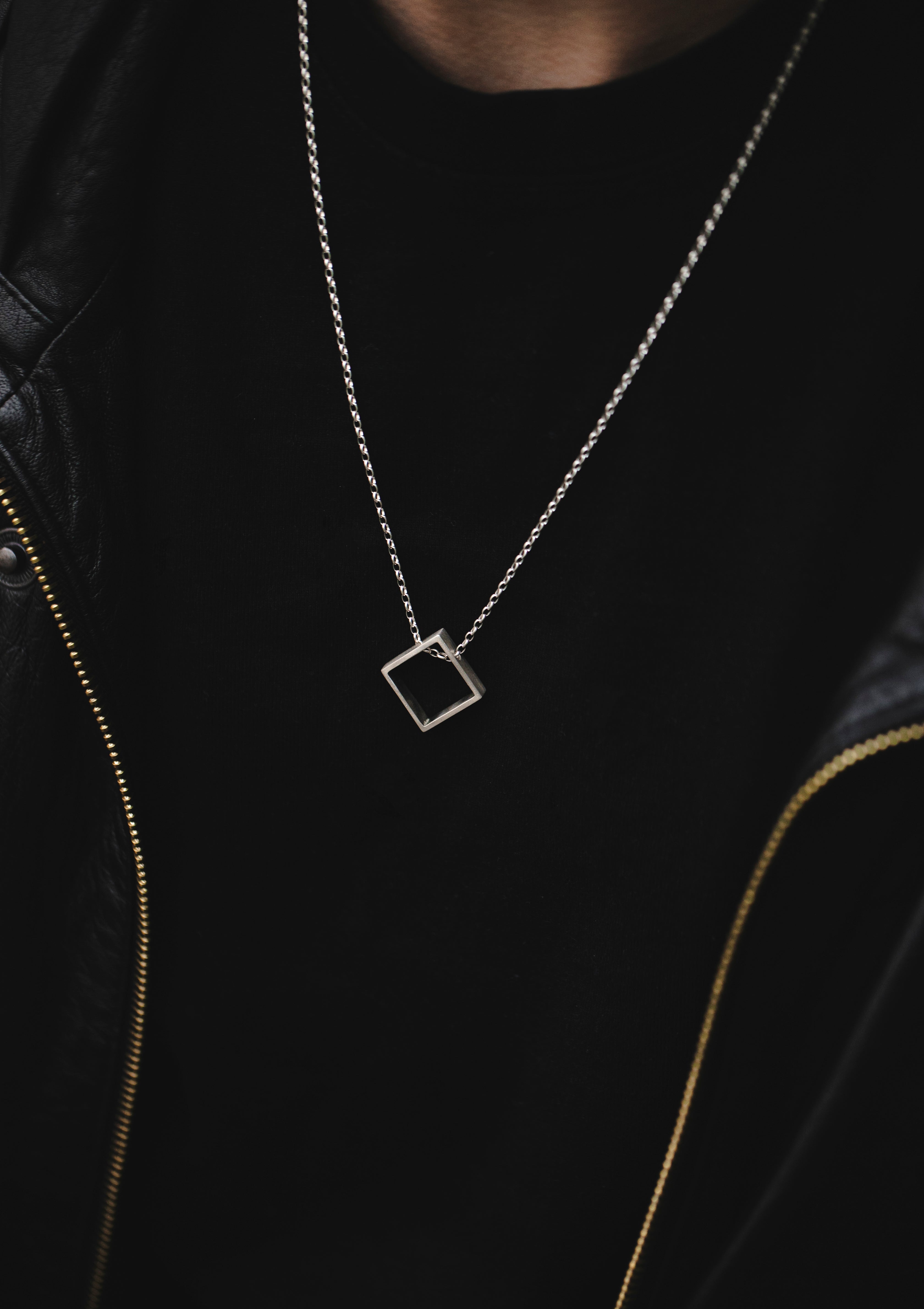 925 silver rhombus necklace worn with dark zippered top, angled pendant adds subtle asymmetry