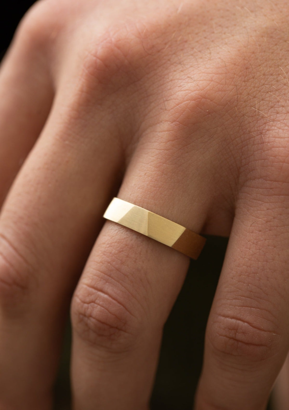 Man wearing 14k faceted gold ring on index finger