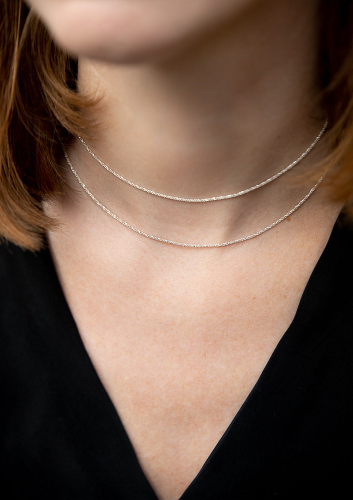 Double-strand sterling silver choker worn with V-neck black top, simple styling emphasizing shine and layering