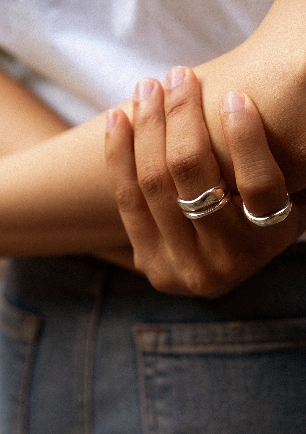 Close-up of ring on crossed arms with white blouse – unisex designer ring for timeless style
