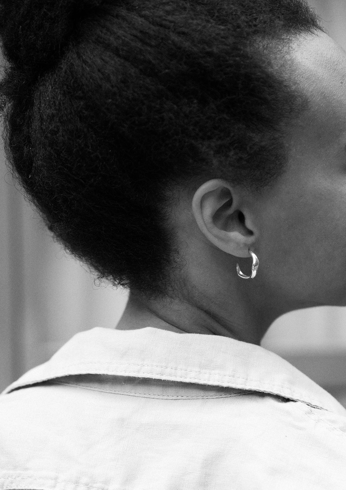 Elegant sterling silver hoops worn in ear, everyday jewelry with gentle wave shape