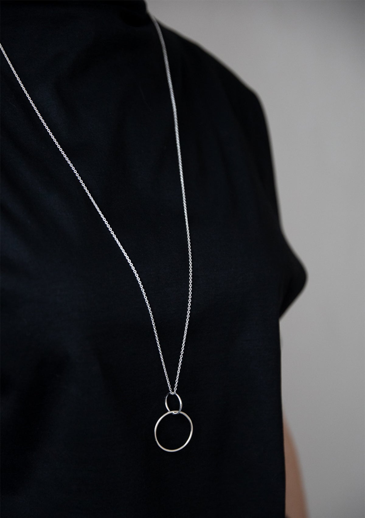 Sterling silver interlocking pendant necklace styled with dark clothing, subtle modern aesthetic