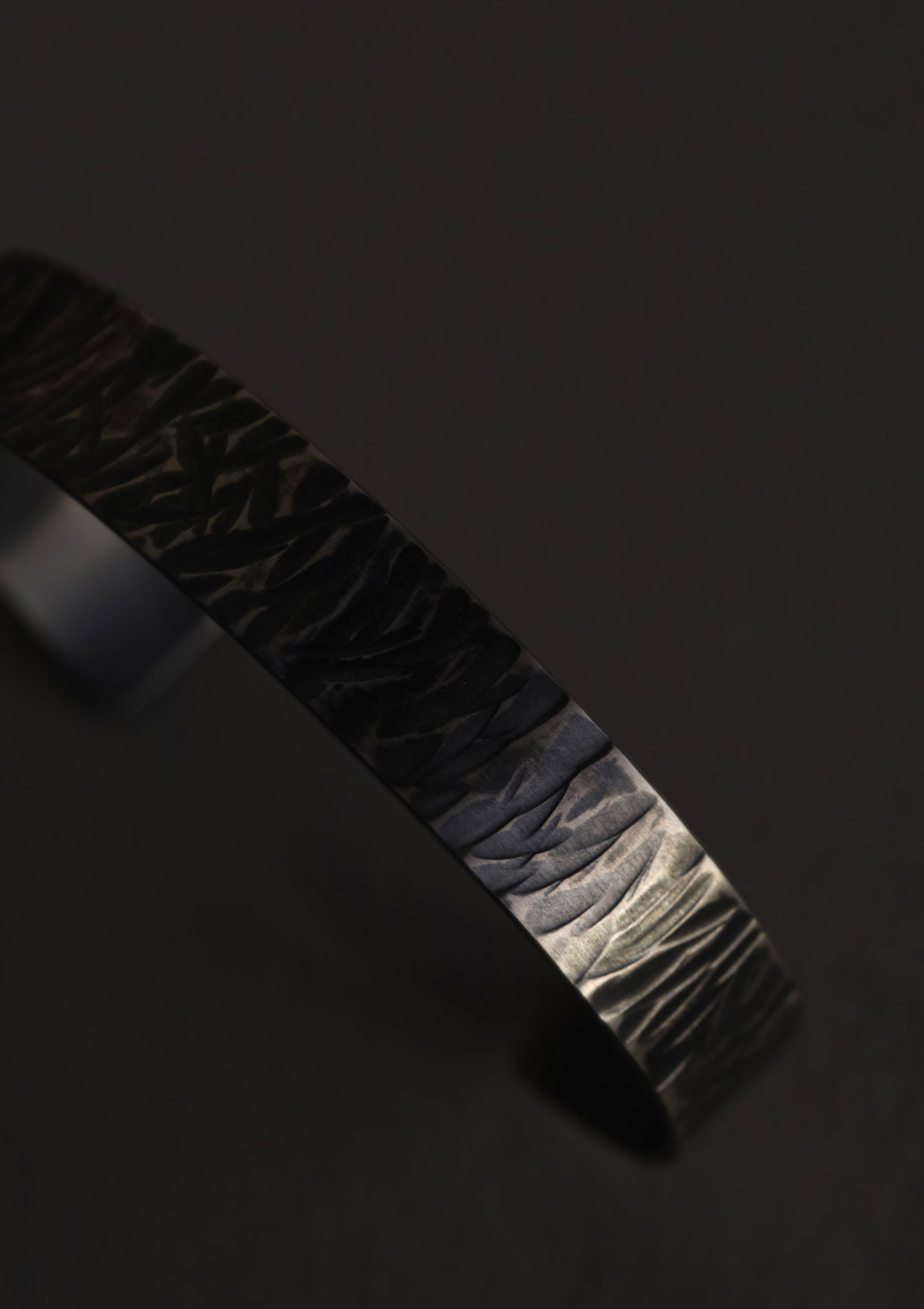 Sterling silver cuff bracelet detail showing hand-forged texture and dark brushed finish