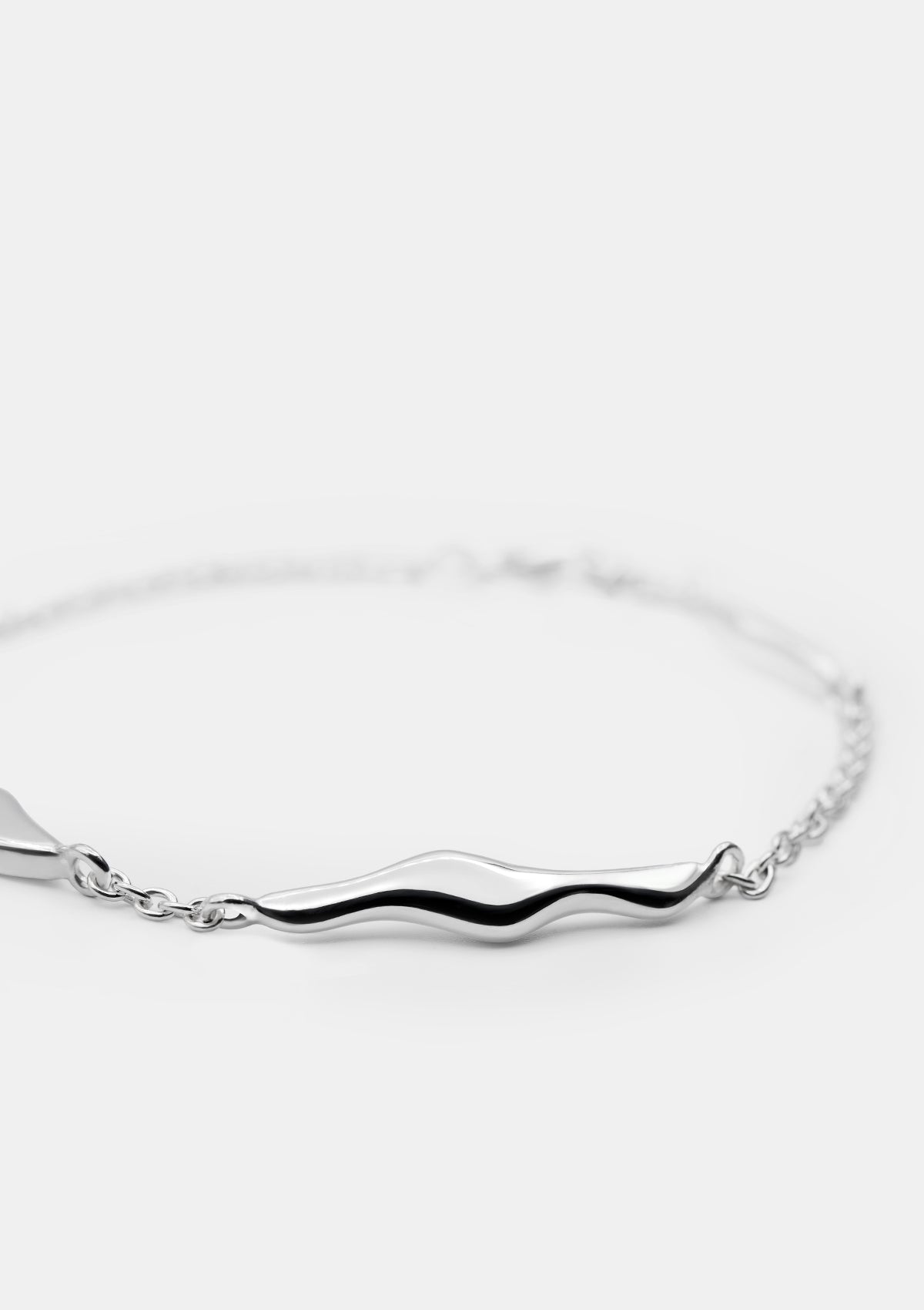 Close-up of silver bracelet featuring sculptural wavy links, refined handmade jewelry detail