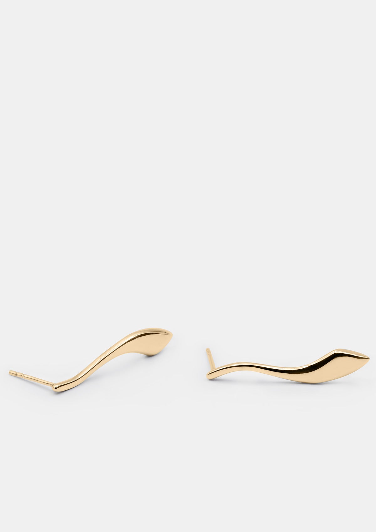 Sculptural long 14K gold earrings photographed diagonally, modern drop studs with flowing form