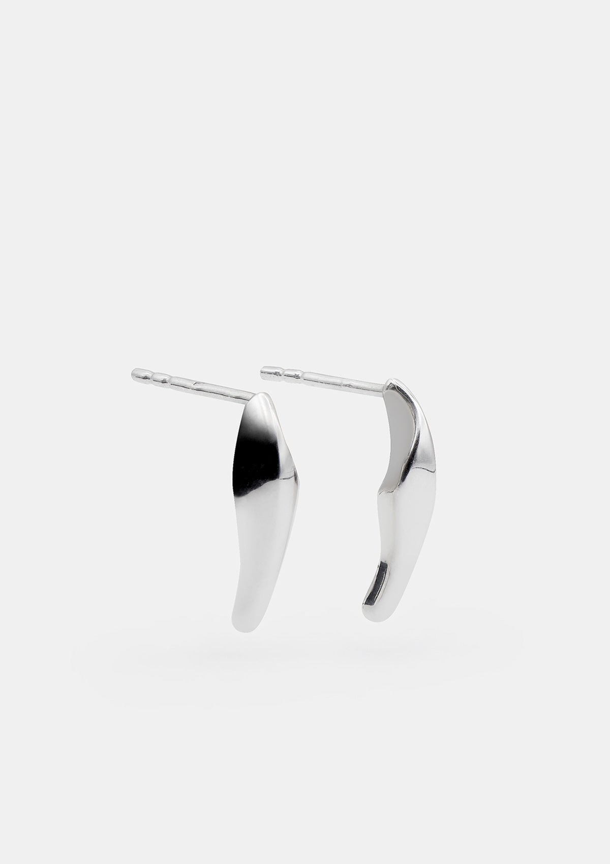 Designer silver earrings arranged in diagonal view, petite modern studs with artisan finish