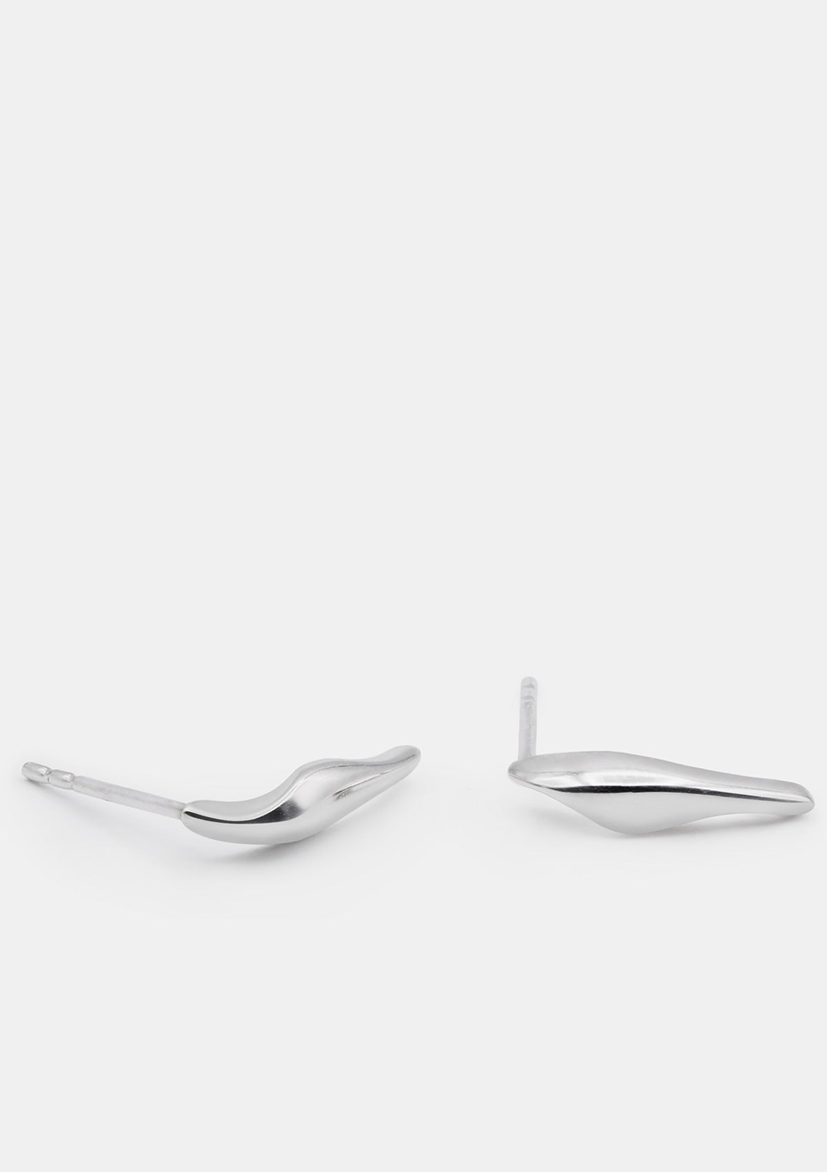 Small sterling silver earrings with soft sculptural curve, photographed flat in minimalist style
