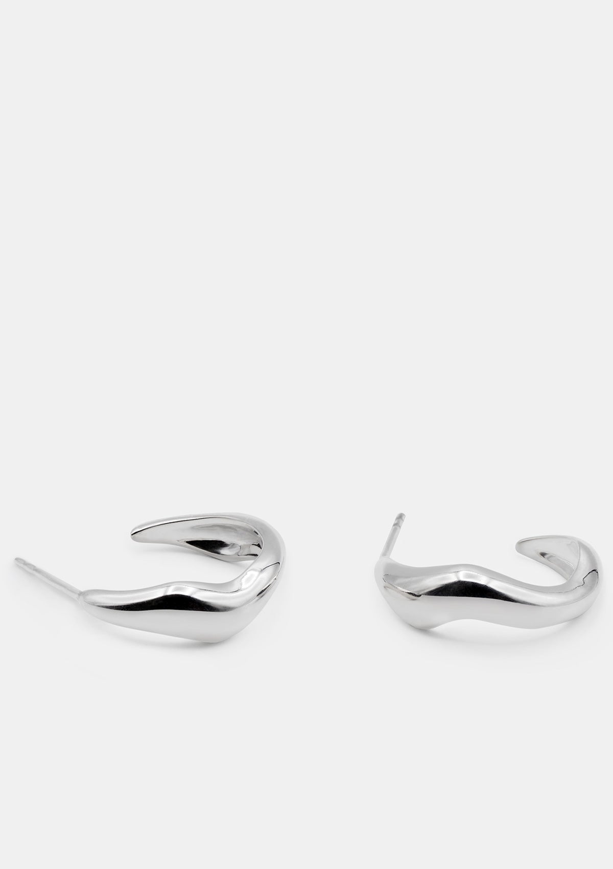 Polished sterling silver hoop earrings with sculptural curved form, modern minimalist design photographed flat