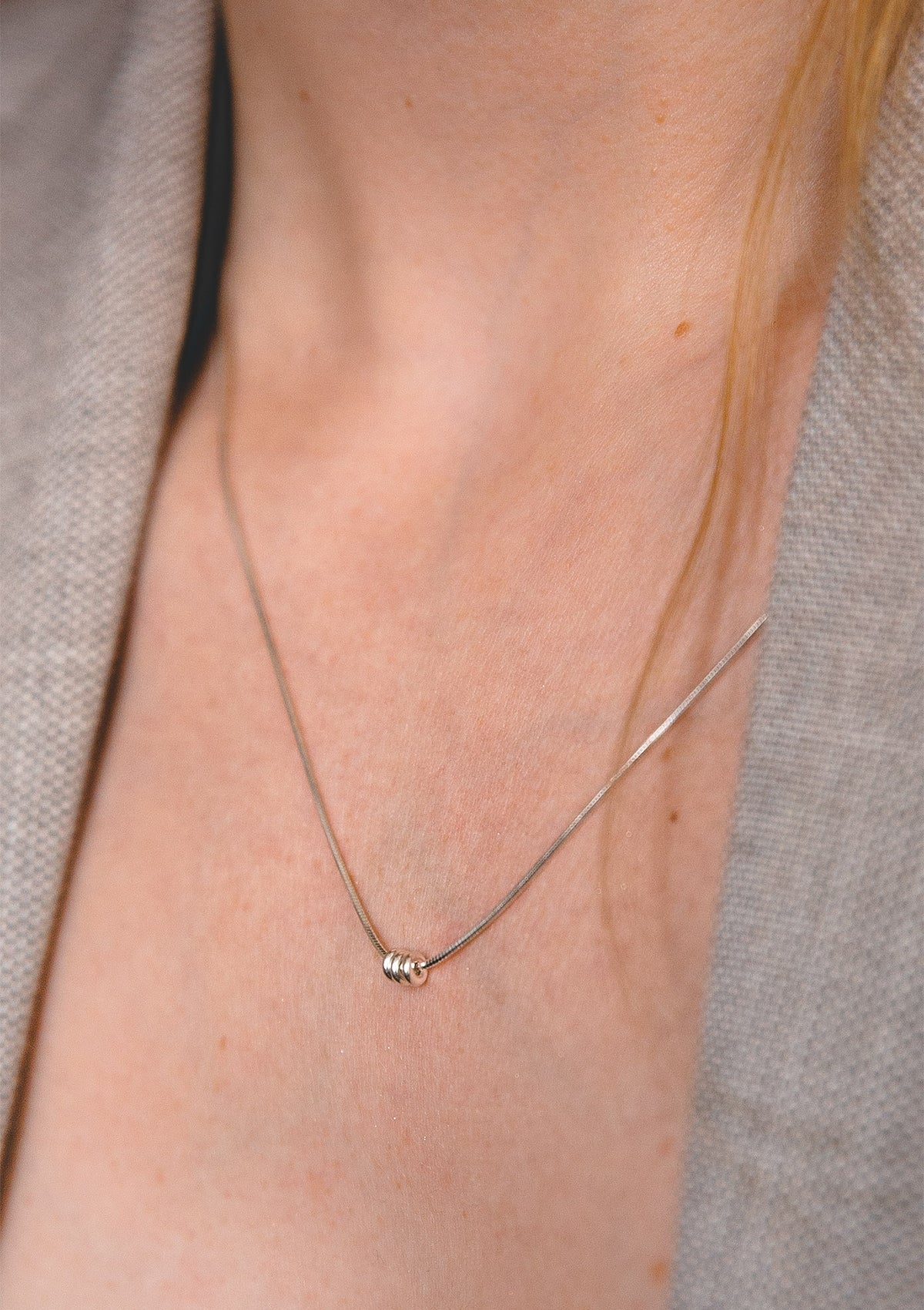Simple silver necklace with trio of tiny spheres, elegant everyday jewelry look with open blazer