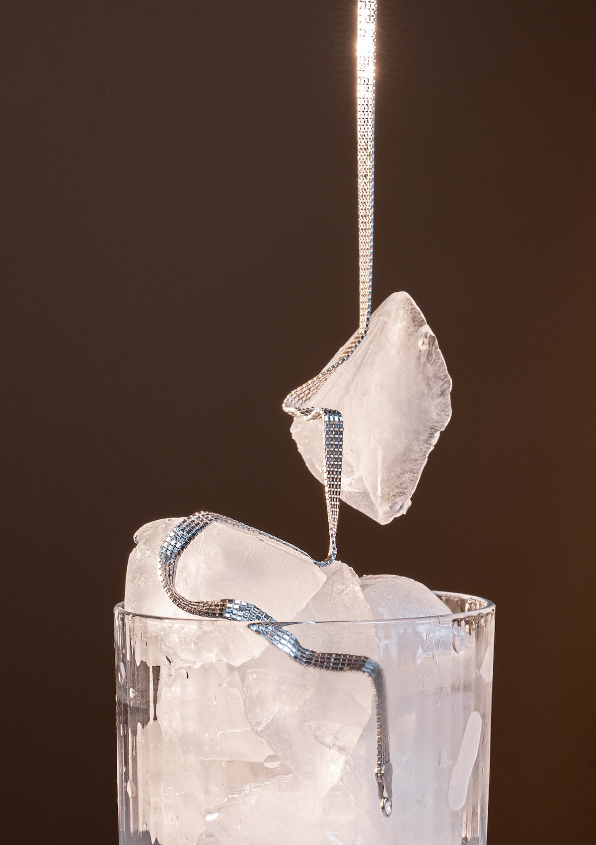 Silver chain choker artistically draped on white quartz-like stone, styled for a clean modern presentation