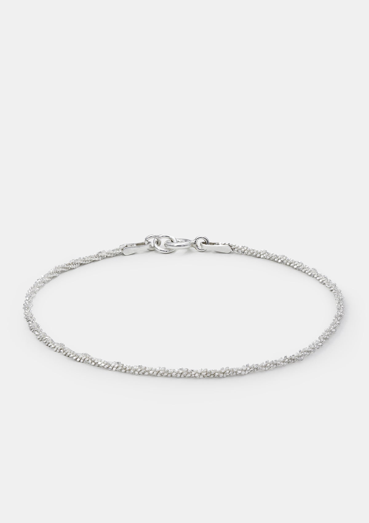 Minimalist sterling silver bracelet with fine sparkling chain, laid flat on soft gray background, modern jewelry design