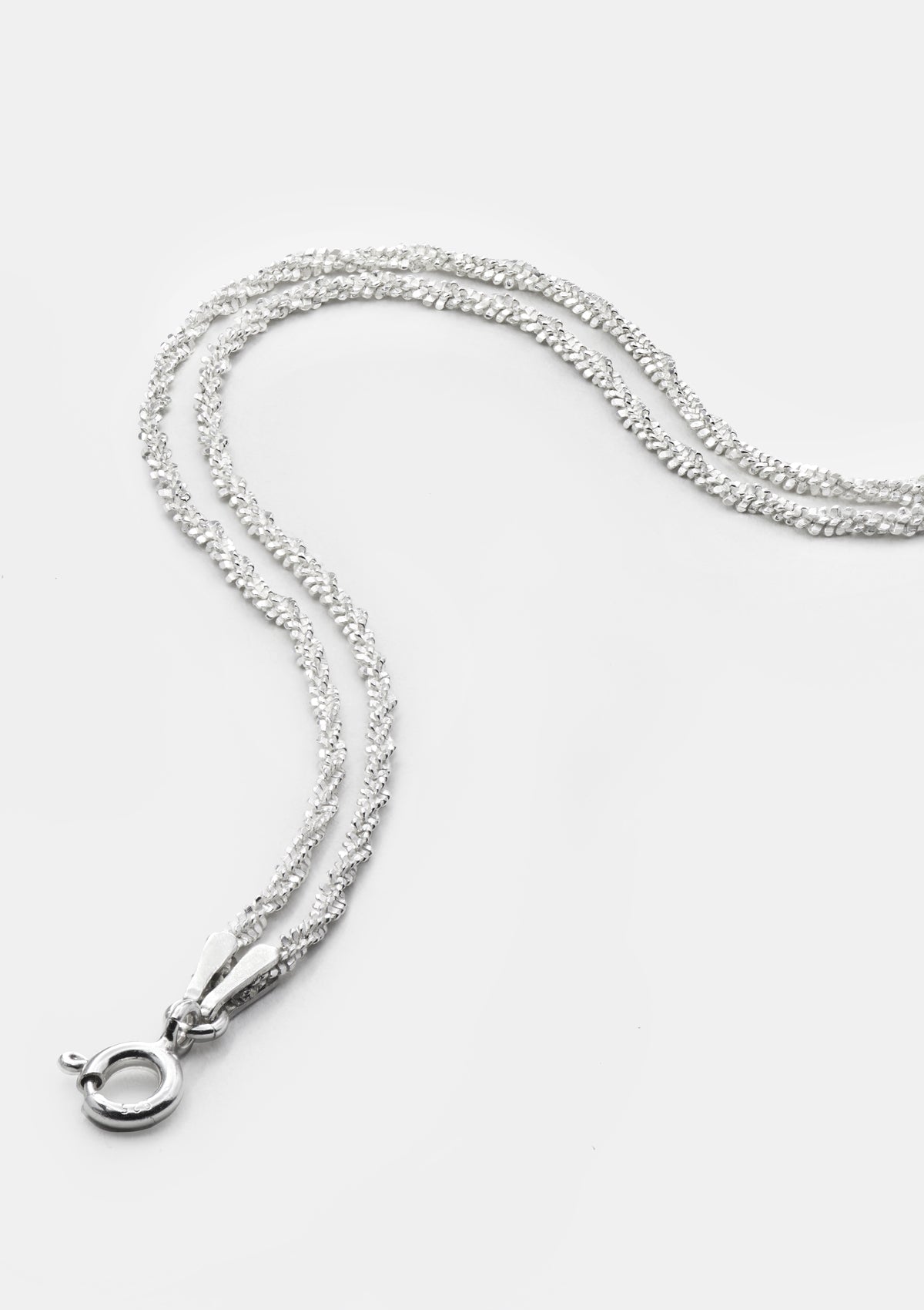 Double-strand silver chain bracelet, minimalist design, linked sterling silver chains laid in curved shape on soft gray background