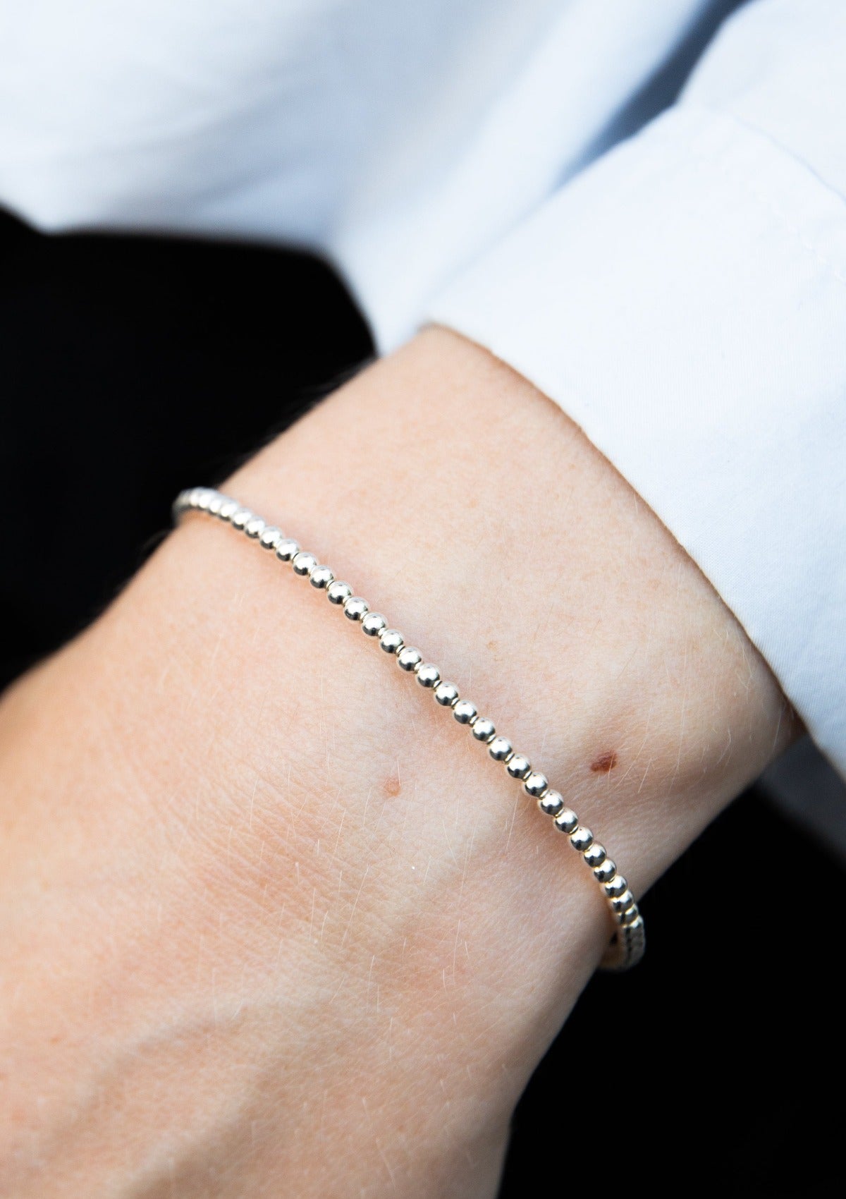 Delicate silver bead bracelet on wrist, minimalist sterling silver layering jewelry, 2 mm handmade stacking bracelet close-up