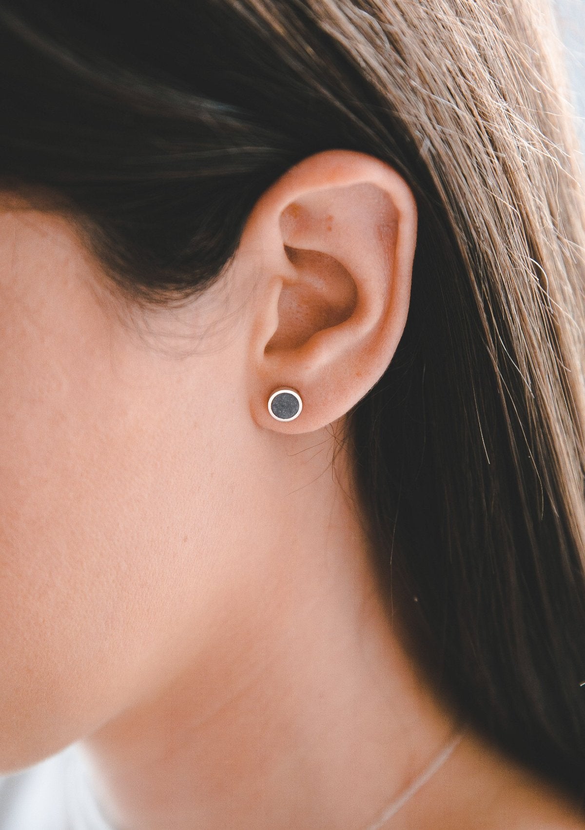 Handcrafted silver and concrete stud earring with round geometric shape, modern design on model's ear
