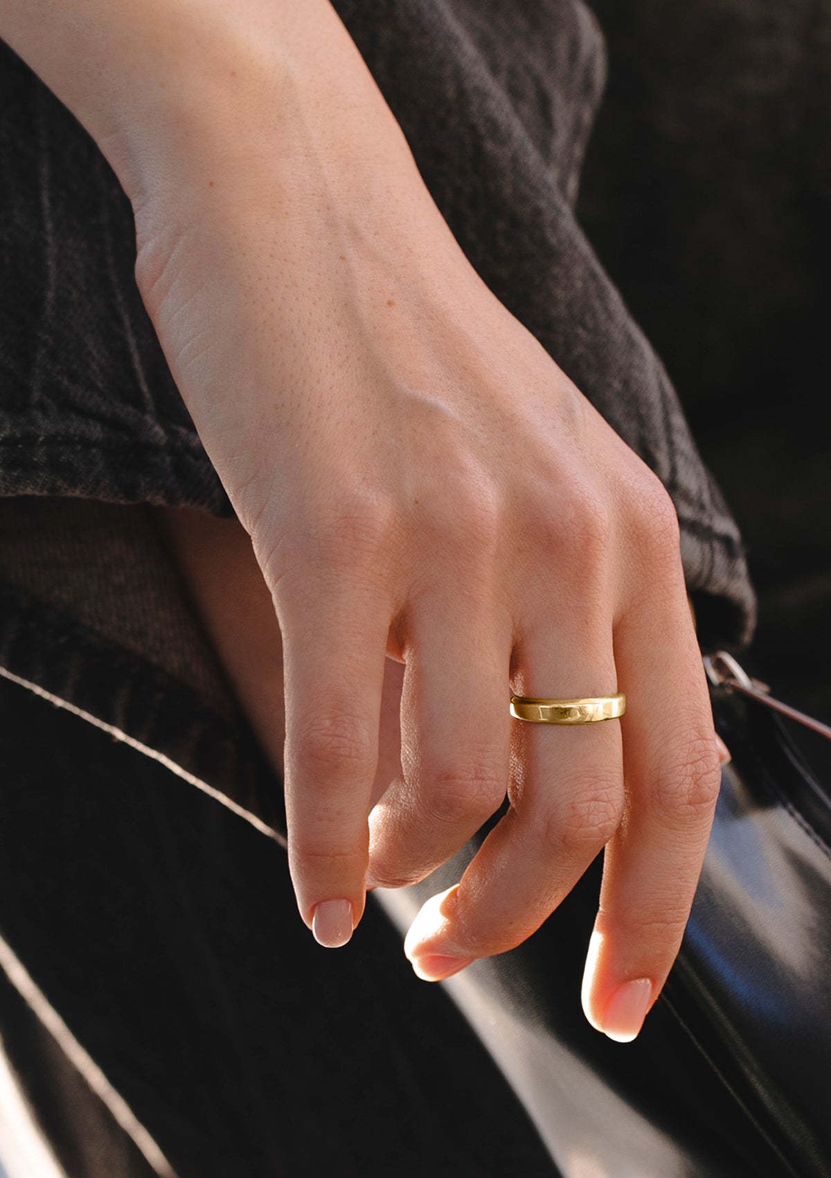 Minimalist gold wedding ring worn on hand, featuring smooth tapering shape