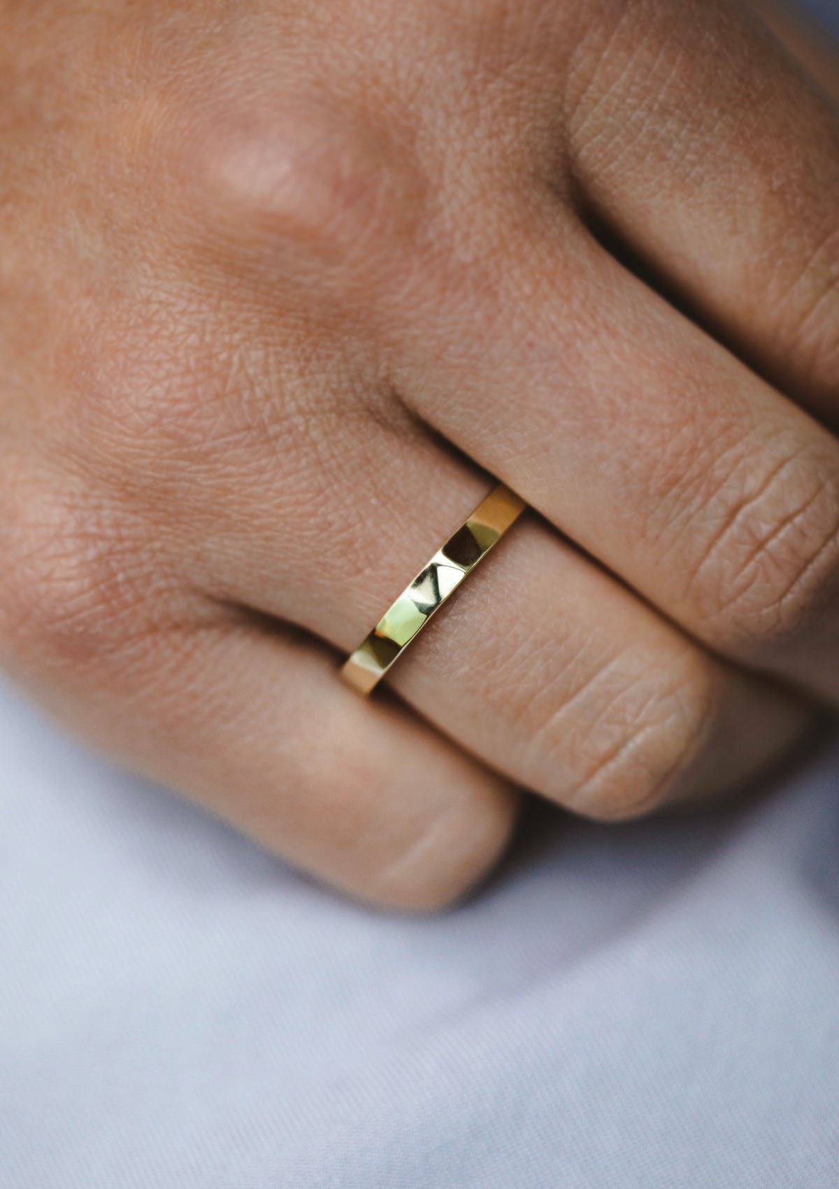 Delicate faceted gold ring worn on woman’s hand – minimalist solid gold band