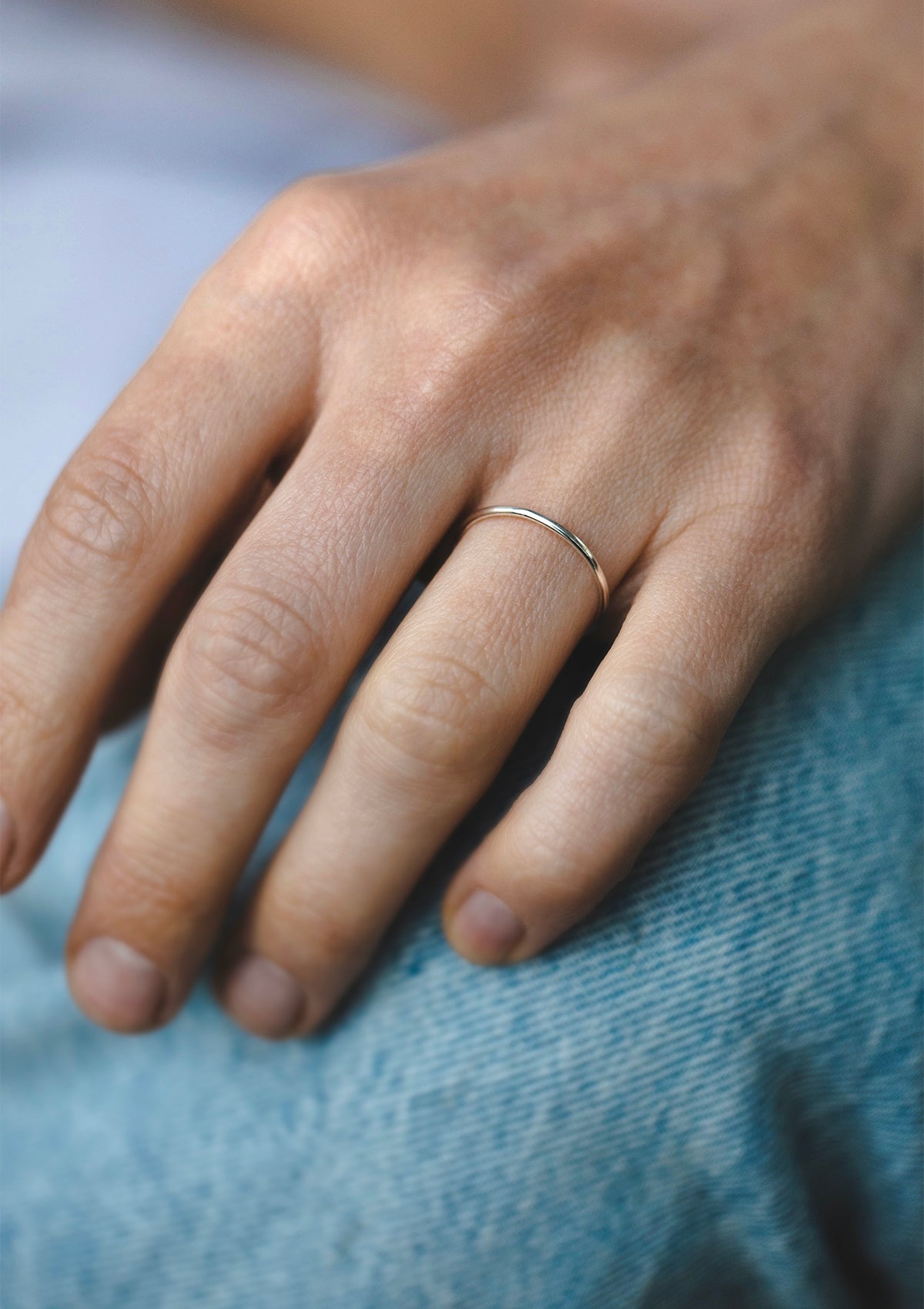 Close-up of silver 1 mm ring worn alone on finger