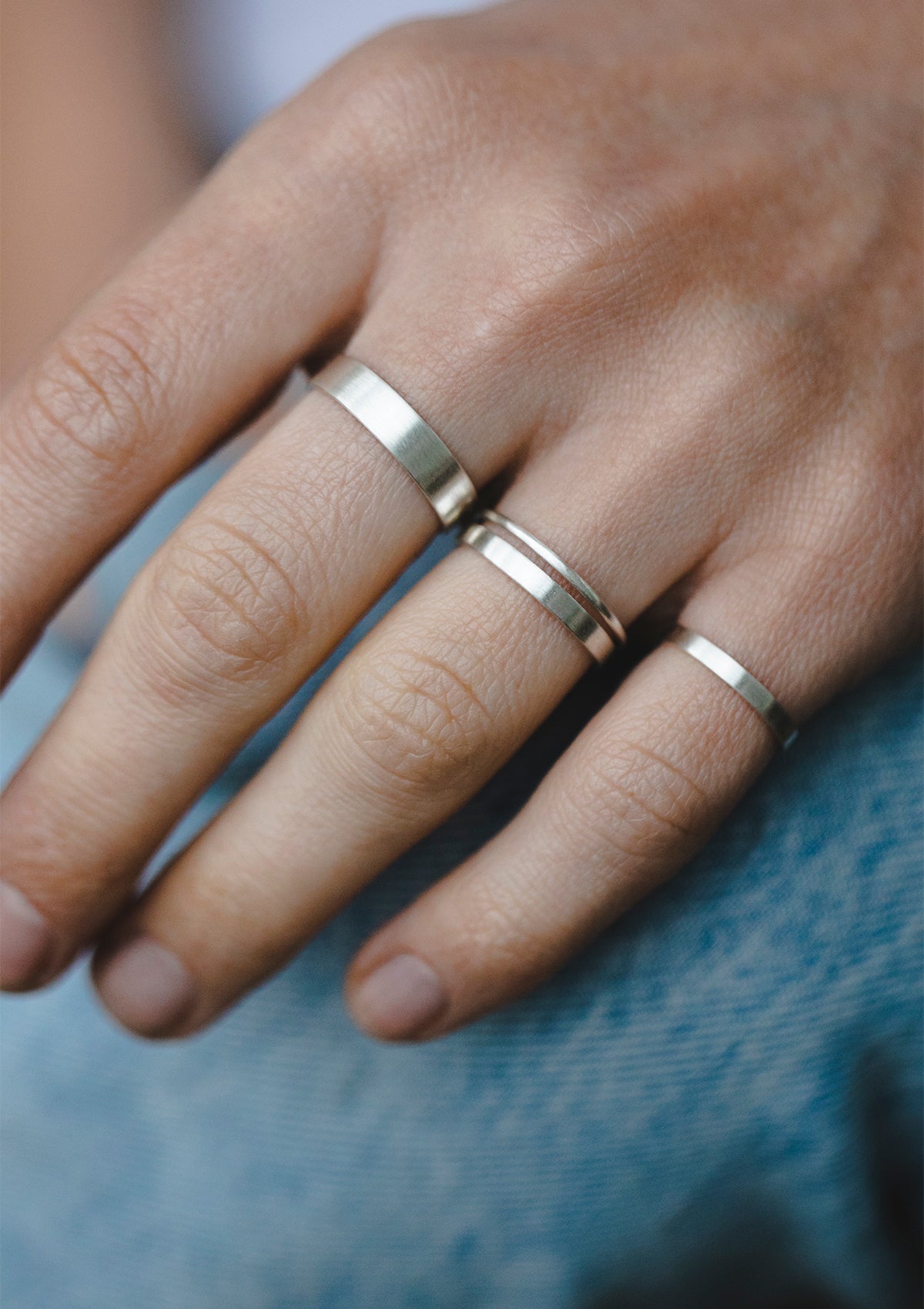 Set of mate sterling silver stacking rings with 4 mm, 2 mm and 1 mm width on model’s hand