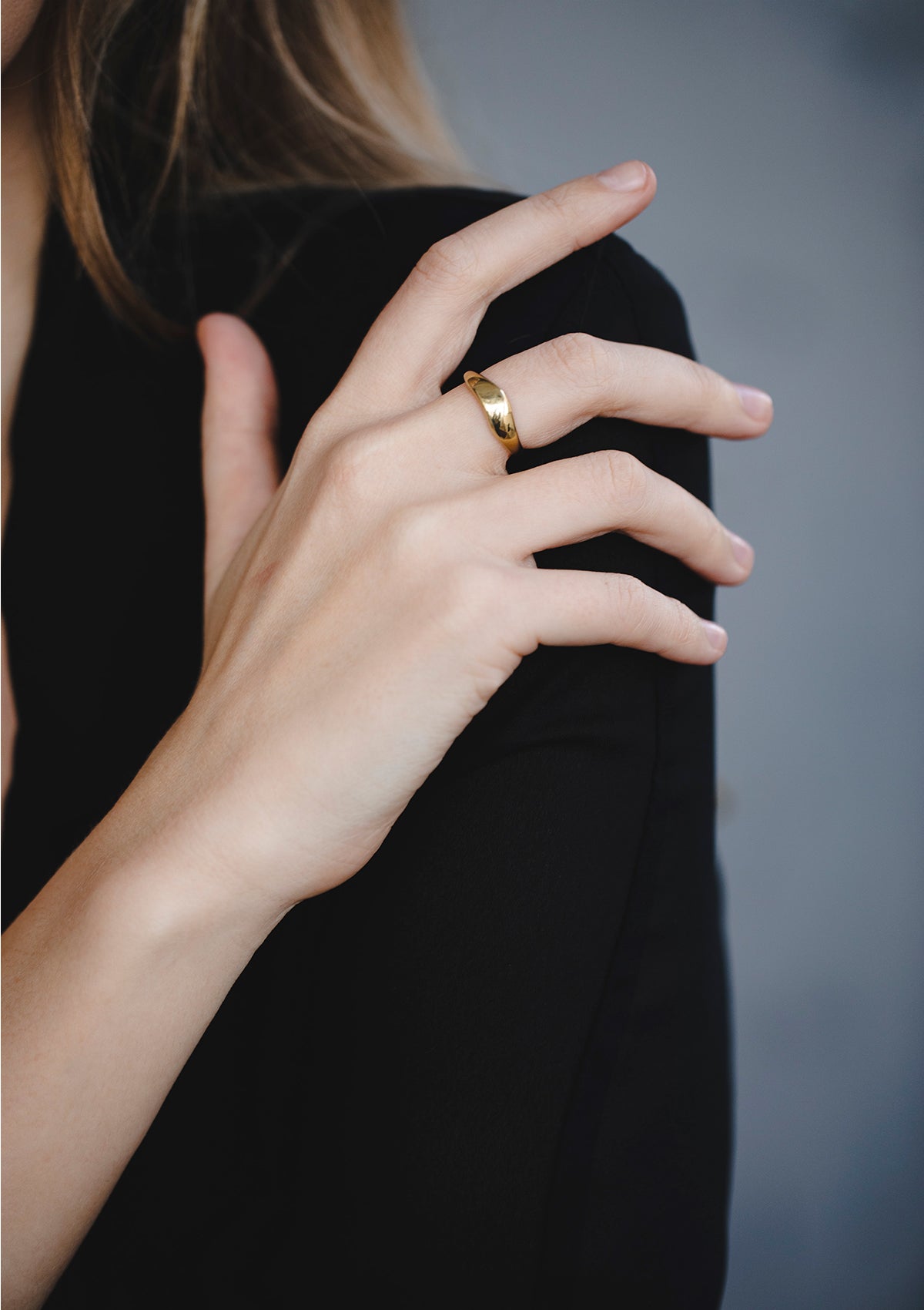 Geometric minimalist gold ring with soft tapered design, styled on hand