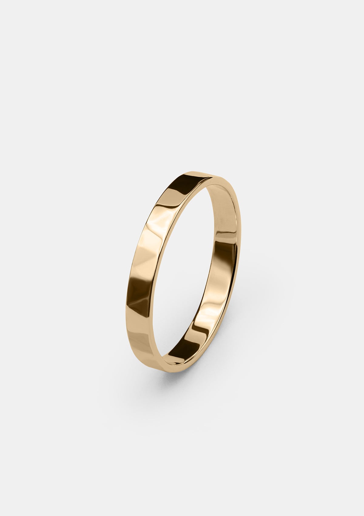 3 mm women's gold wedding ring with hammered faceted surface on light gray background