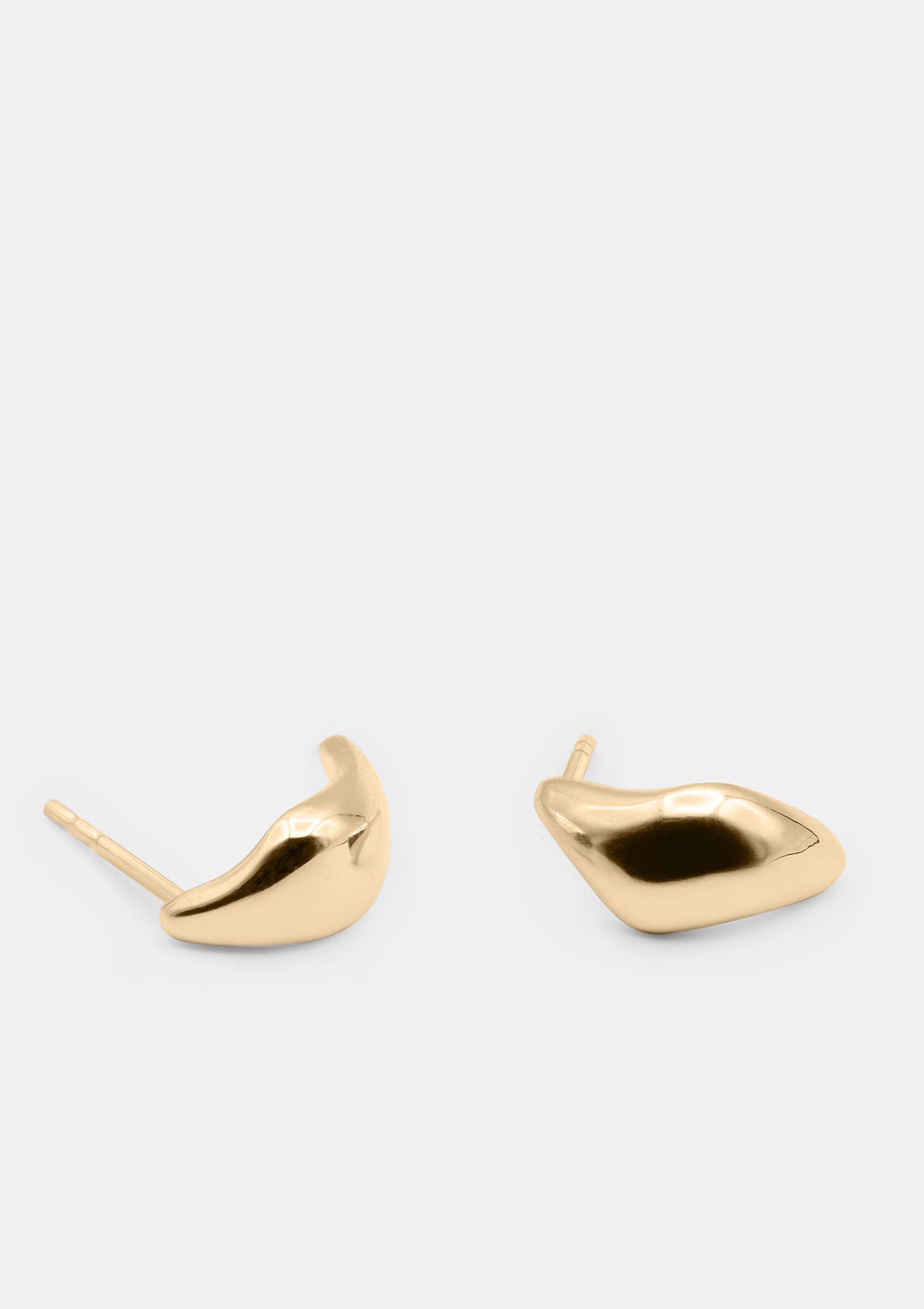 Pair of sculptural 14k yellow gold huggie earrings on white background