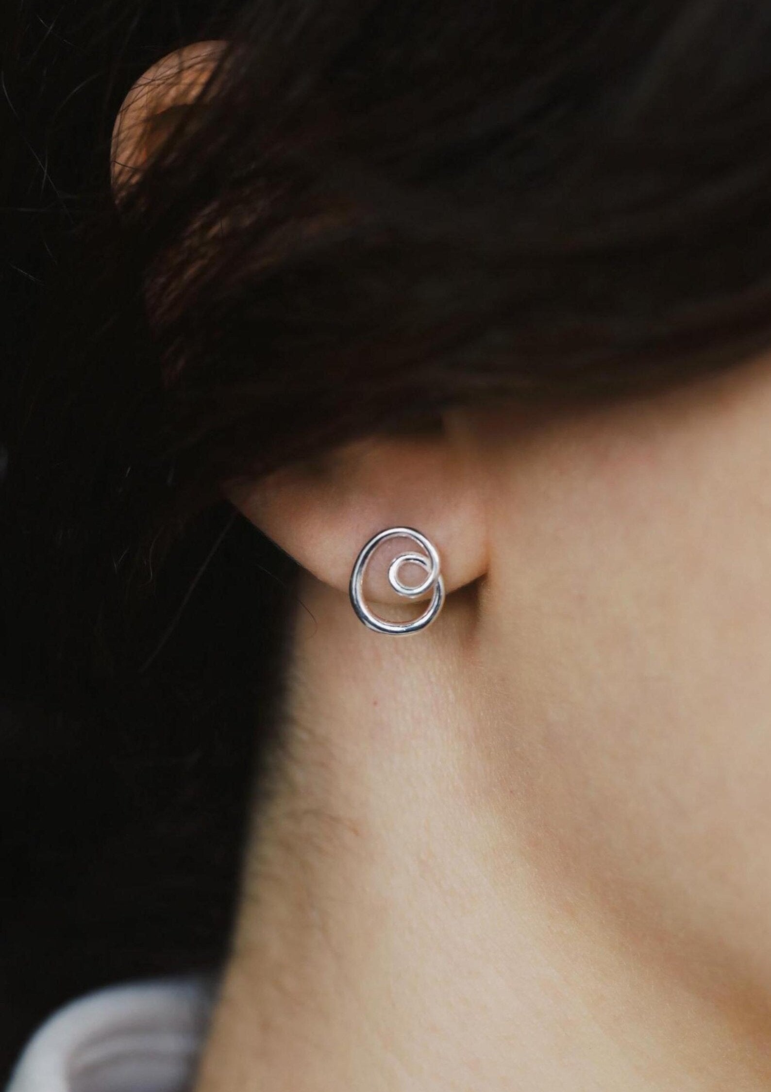  an ear wearing a silver hoop earring minimalistic